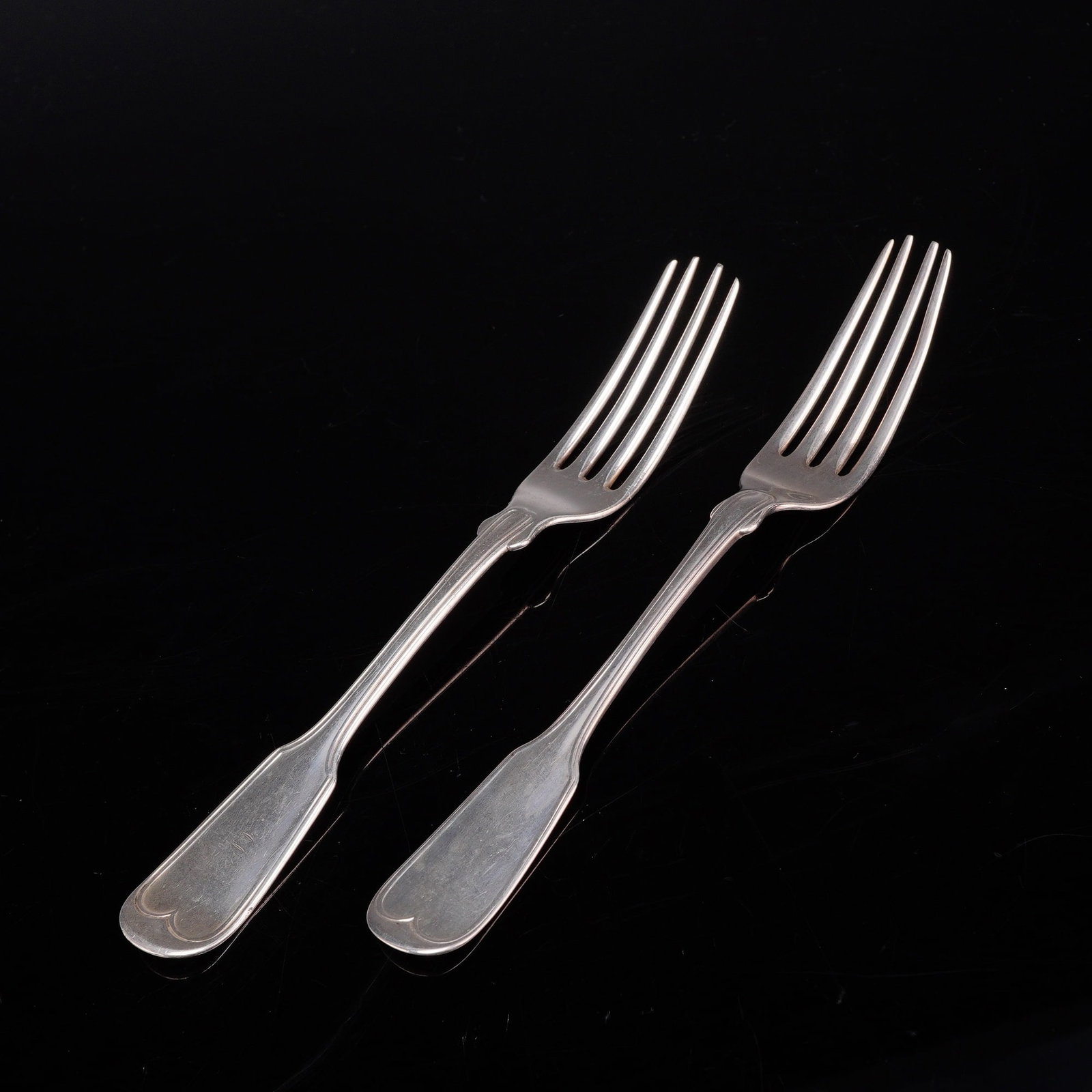 A Pair of Mitchell & Tyler Coin Silver Dinner Forks: A pair of coin silver dinner forks with a heart-shaped scroll at the handle terminal. The reverse of the handles is stamped with the maker mark MITCHELL & TYLER. One fork handle is engraved with a