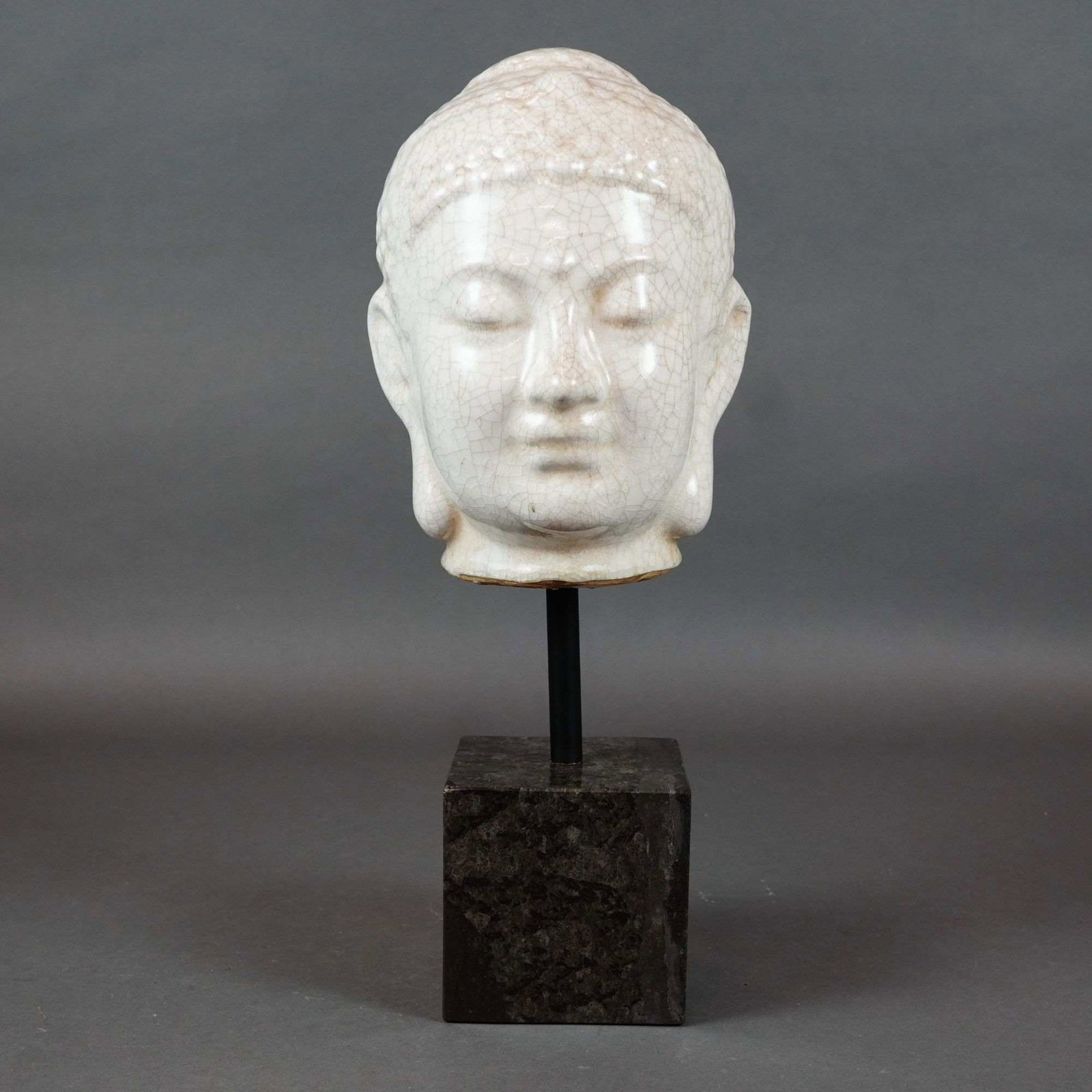 Buddha Head Sculpture in Crackle-Glaze Ceramic on Marble Stand: A decorative ceramic Buddha head sculpture featuring a thick, cream-colored glaze with a dense and prominent crackle pattern throughout in the style of traditional Chinese Ge-type wares. The head is m