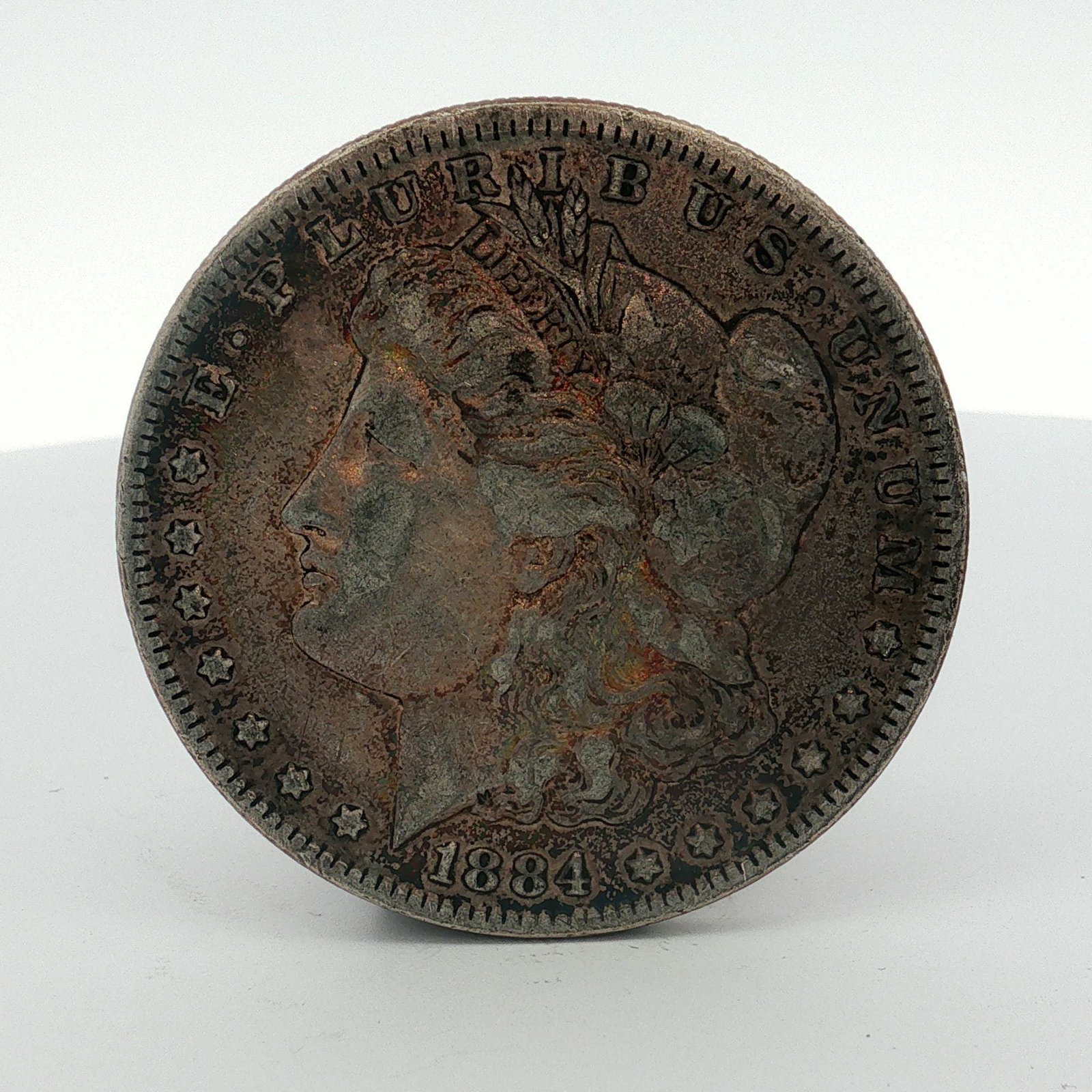 1884 US Morgan Silver Dollar Coin Circulated: US 1884 Morgan silver dollar struck at the Philadelphia Mint. This coin is composed of .900 fine silver. The design features the Liberty Head obverse and the heraldic eagle reverse. This specimen lack