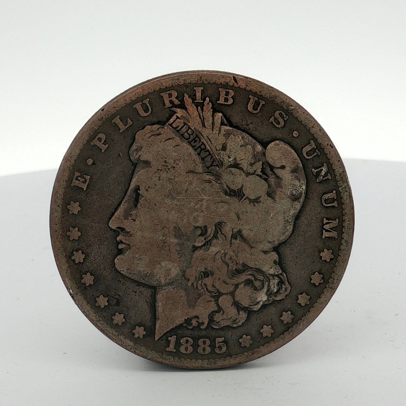 1885 US Morgan Silver Dollar Coin Circulated: This US Morgan silver dollar was struck at the Philadelphia Mint in 1885. The coin is composed of 90% silver and 10% copper. It features the Liberty head obverse and the heraldic eagle reverse. The