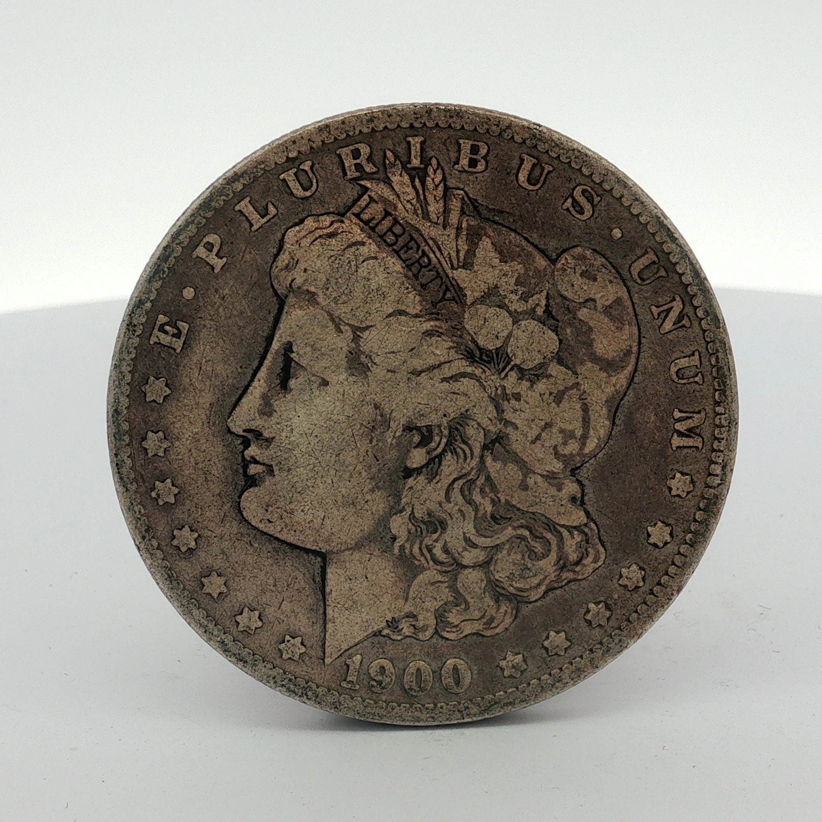 1900-O US Morgan Silver Dollar Coin Circulated: This US silver coin is a Morgan dollar struck at the New Orleans Mint. The piece is composed of 90 percent silver and 10 percent copper. The obverse features the Morgan design with the 1900 date and t