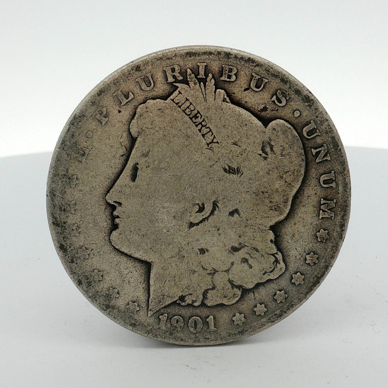 1901-O US Morgan Silver Dollar: This US silver Morgan dollar was minted at the New Orleans facility in 1901. The coin is struck in 90% silver. It features the Liberty Head obverse and the heraldic eagle reverse. The O mint mark is p