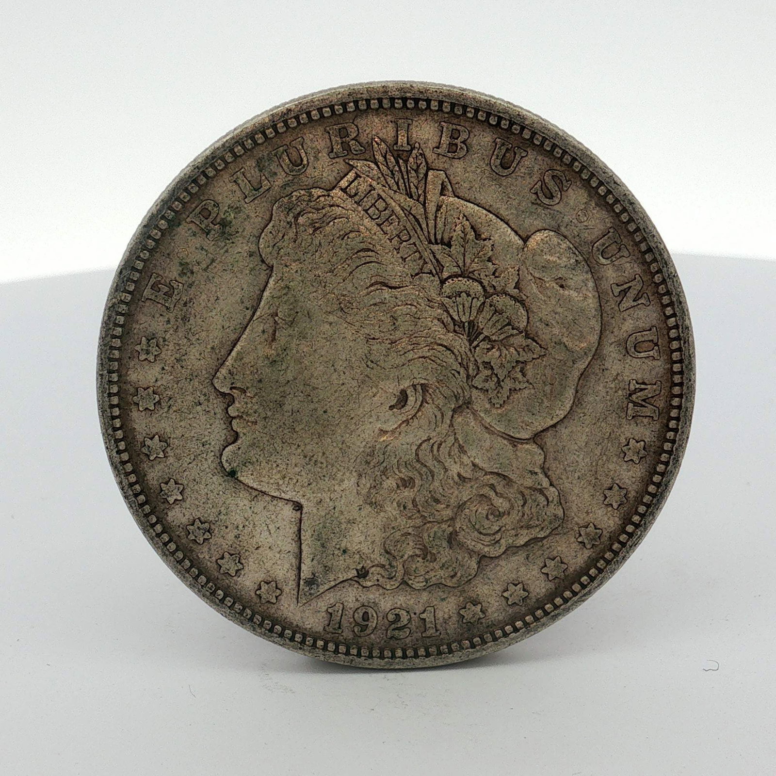 1921 US Morgan Silver Dollar Coin Circulated: This 1921 US Morgan dollar is struck in a 90% silver alloy (.900 fineness). The obverse features the Morgan dollar design with the date 1921 and the legend E PLURIBUS UNUM. The reverse features a hera