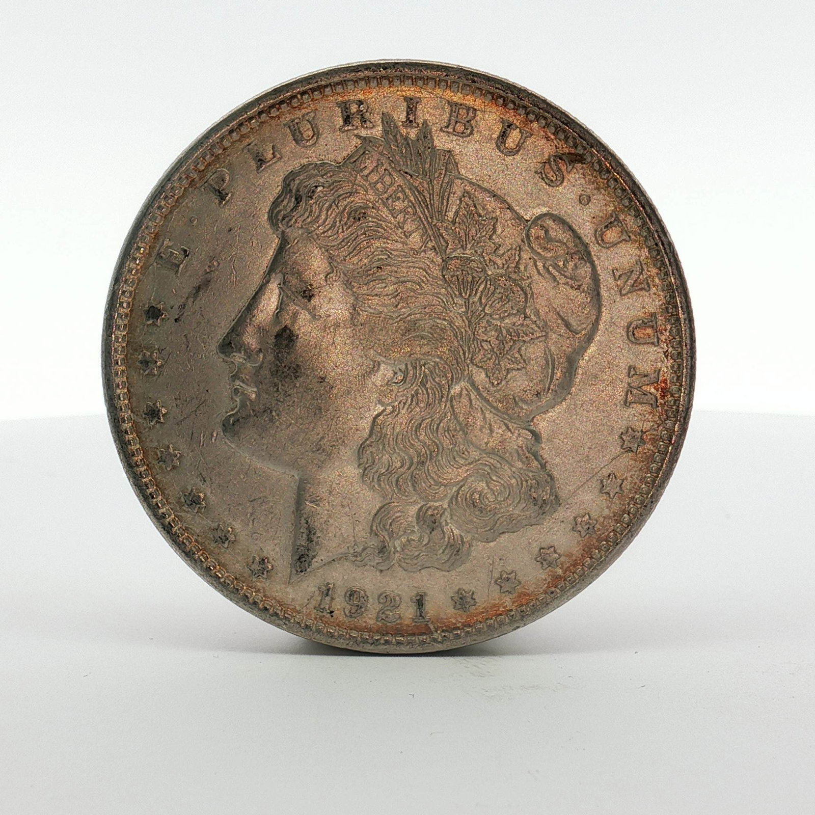1921-D US Morgan Silver Dollar Coin Circulated: This US silver coin is a Morgan dollar struck at the Denver Mint. The piece features the Morgan obverse and Morgan reverse designs. Inscriptions include E PLURIBUS UNUM and the date 1921 on the obvers