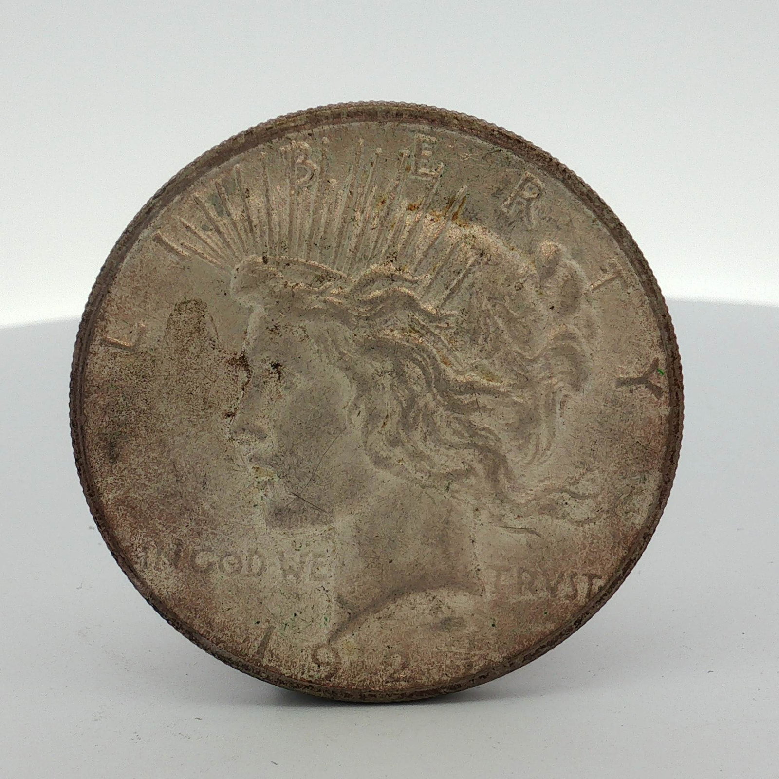 1927-S US One Dollar Peace Silver Dollar Coin, Circulated: A 1927 US Peace silver dollar. This specimen is composed of 90 percent silver and 10 percent copper. The obverse features the standard Peace dollar Liberty design with inscriptions LIBERTY, IN GOD WE 