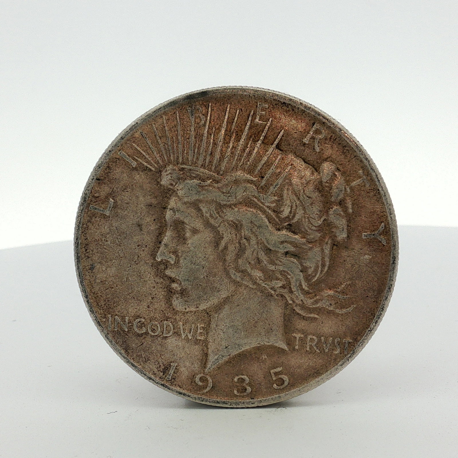1935-S US One Dollar Peace Silver Dollar Coin, Circulated: This US 1935-S Peace silver dollar is composed of 90% silver and 10% copper. The coin features the standard Peace dollar obverse and reverse designs. Obverse inscriptions include LIBERTY, IN GOD WE TR