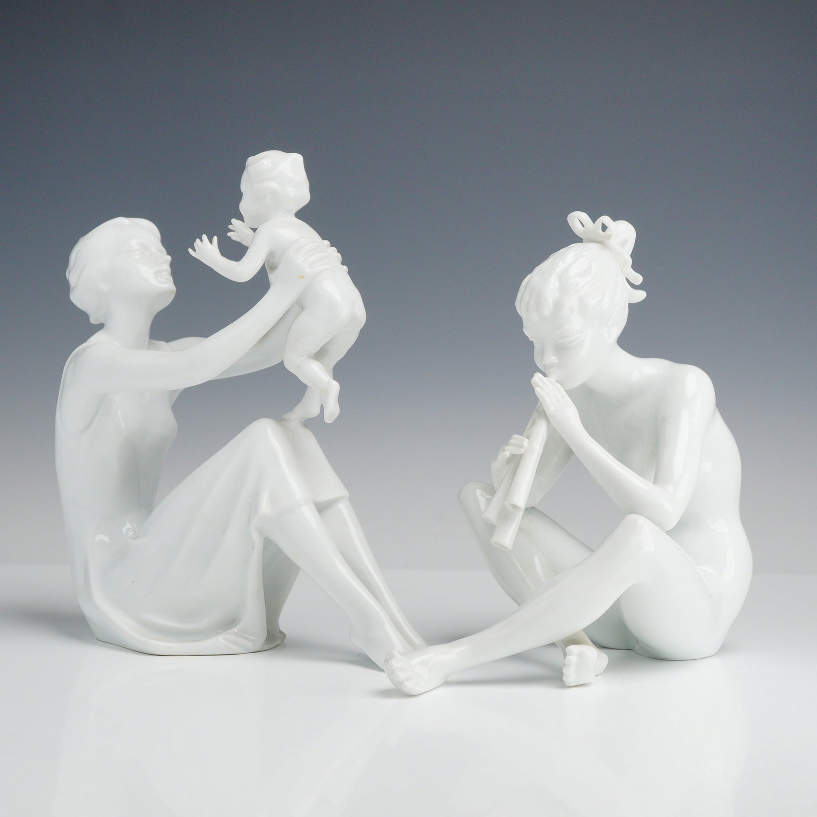 Two Kaiser White Glazed Porcelain Figurines Mother and Child and Flute Player: A group of white glazed porcelain figurines manufactured by the Kaiser porcelain factory (formerly Alka-Kunst) in West Germany. The first figurine, titled Mother and Child, depicts a seated female
