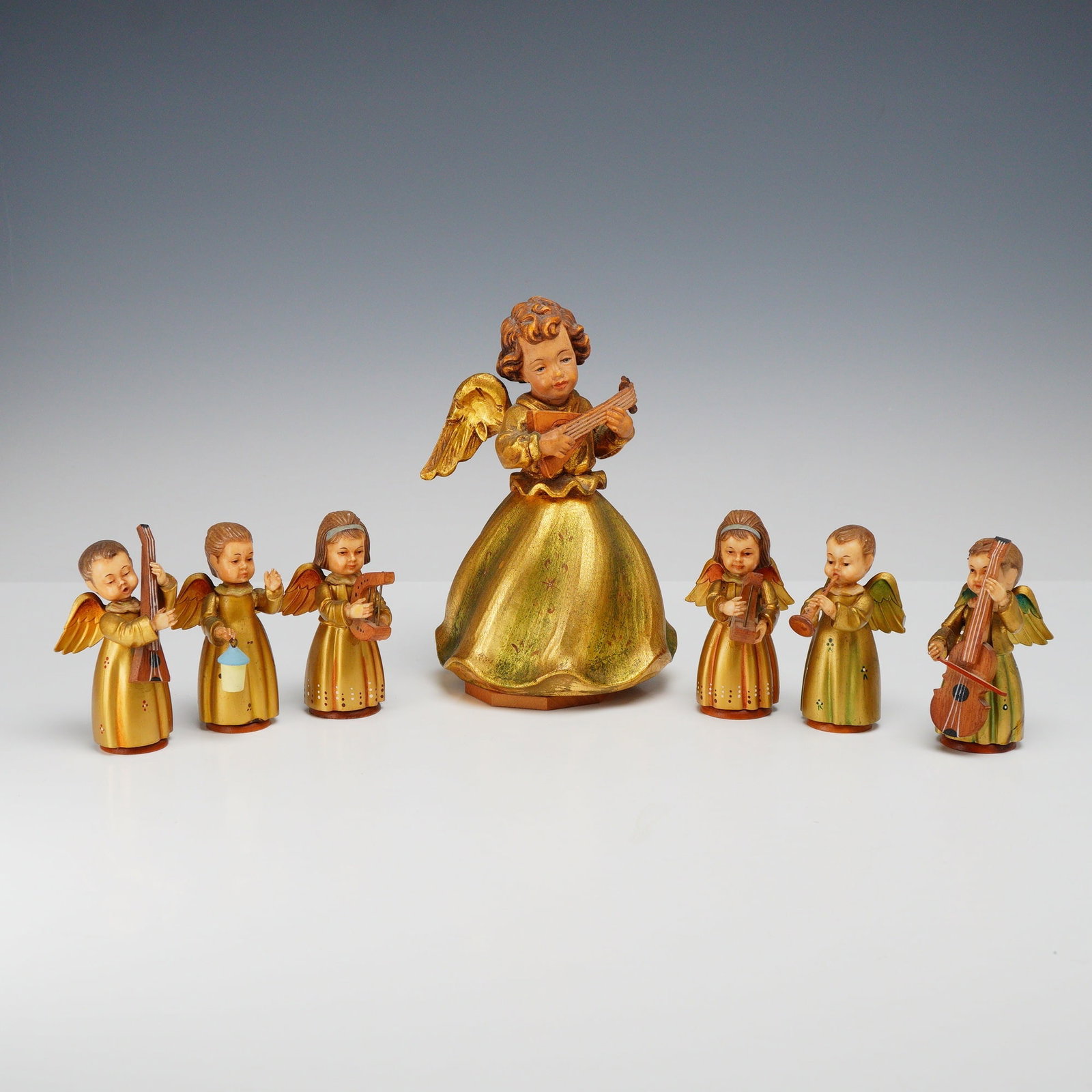 Lot of 7 Toriart Italy Angel Figurines Including One Musical Example: A lot of seven Toriart Italy hand-painted wooden angel figurines, including one large central musical figure and six smaller musician figures. Produced in the Val Gardena region of Italy by Toriart, a