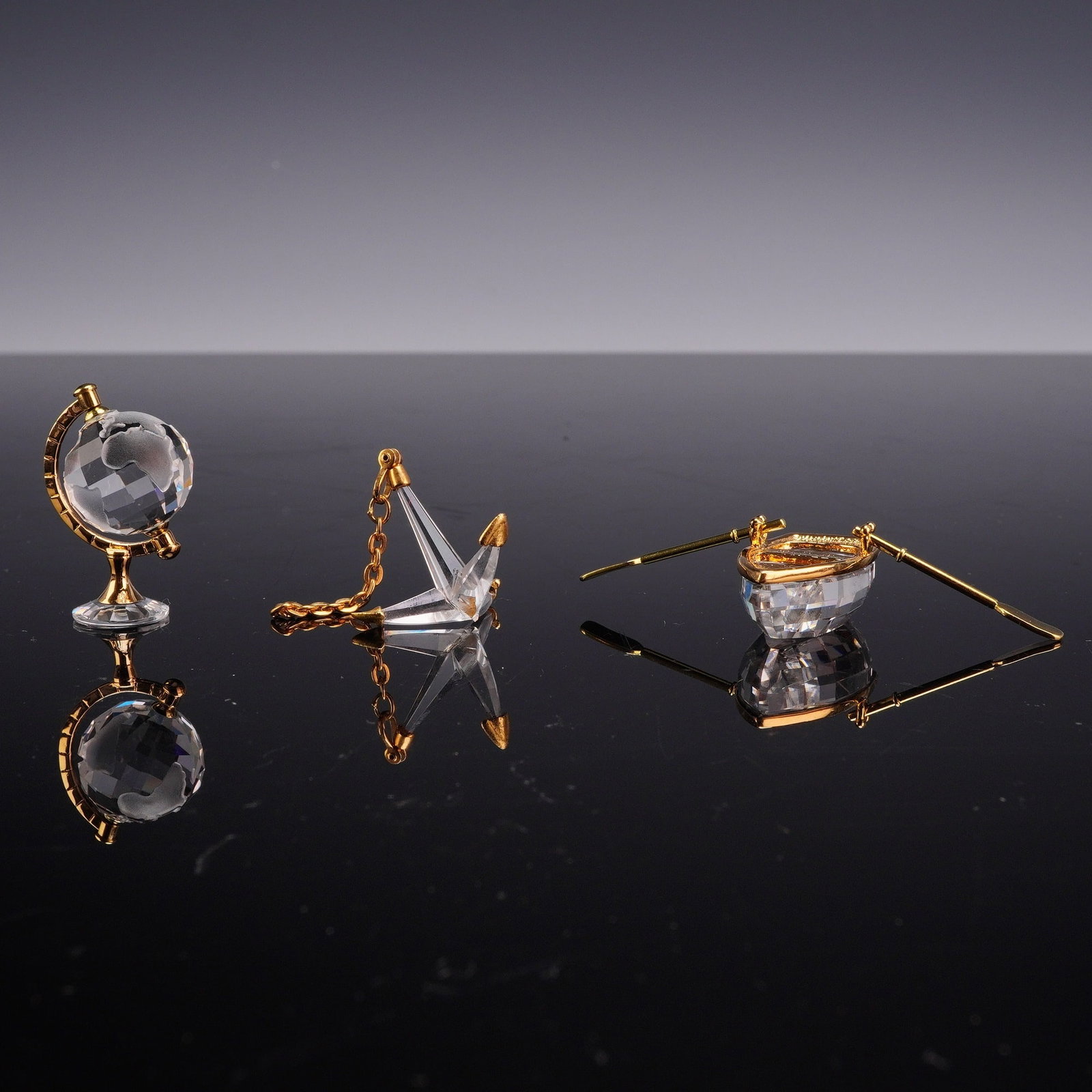 3pc Swarovski Crystal Memories Figurines, Globe, Anchor, and Rowboat: Each crafted from faceted lead crystal with gold-plated metal accents. The collection includes a globe with a faceted crystal sphere and frosted continents on a gold-plated metal stand, a faceted crys
