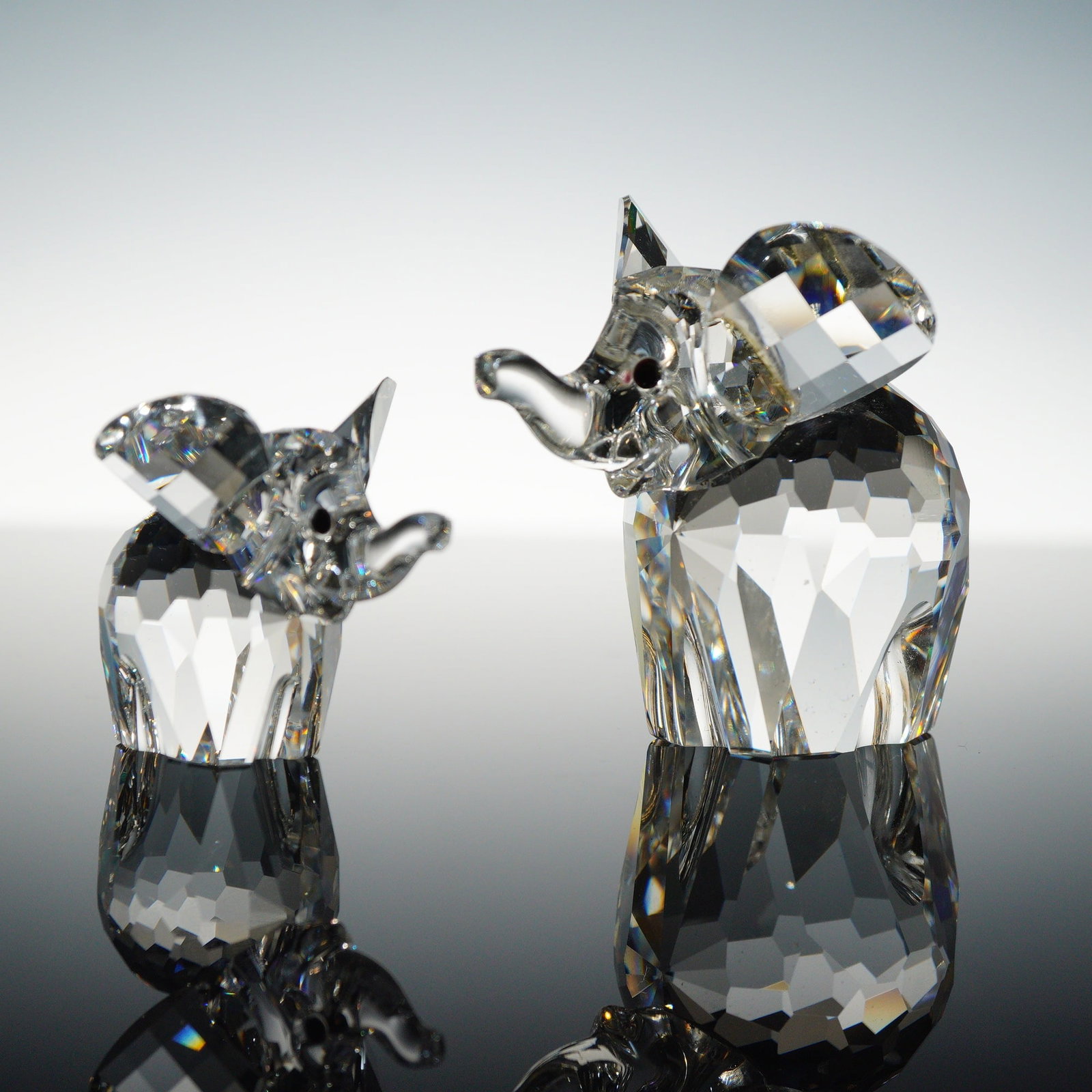 A Lot of Two Swarovski Silver Crystal Elephant Figurines with Boxes: A lot of two Swarovski clear lead crystal elephant figurines, consisting of one larger adult and one smaller calf from the Silver Crystal collection. Both figurines feature faceted bodies, raised trun