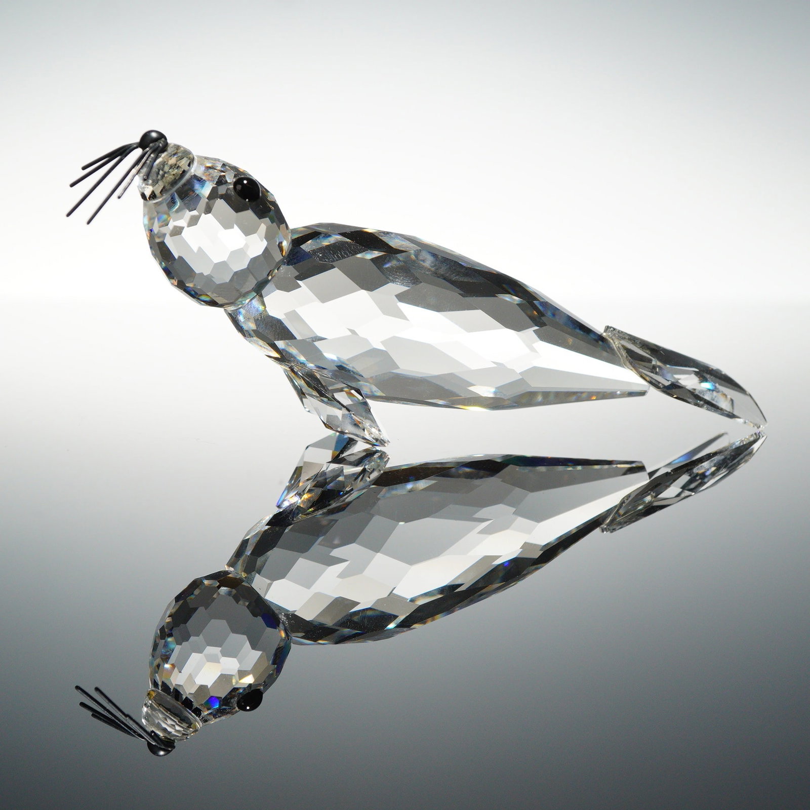 Swarovski Silver Crystal Large Seal Figurine with Whiskers and Original Box: A Swarovski lead crystal figurine depicting the Large Seal model from the Silver Crystal collection. The piece is constructed from faceted clear crystal and features two small black cabochon eyes. Six