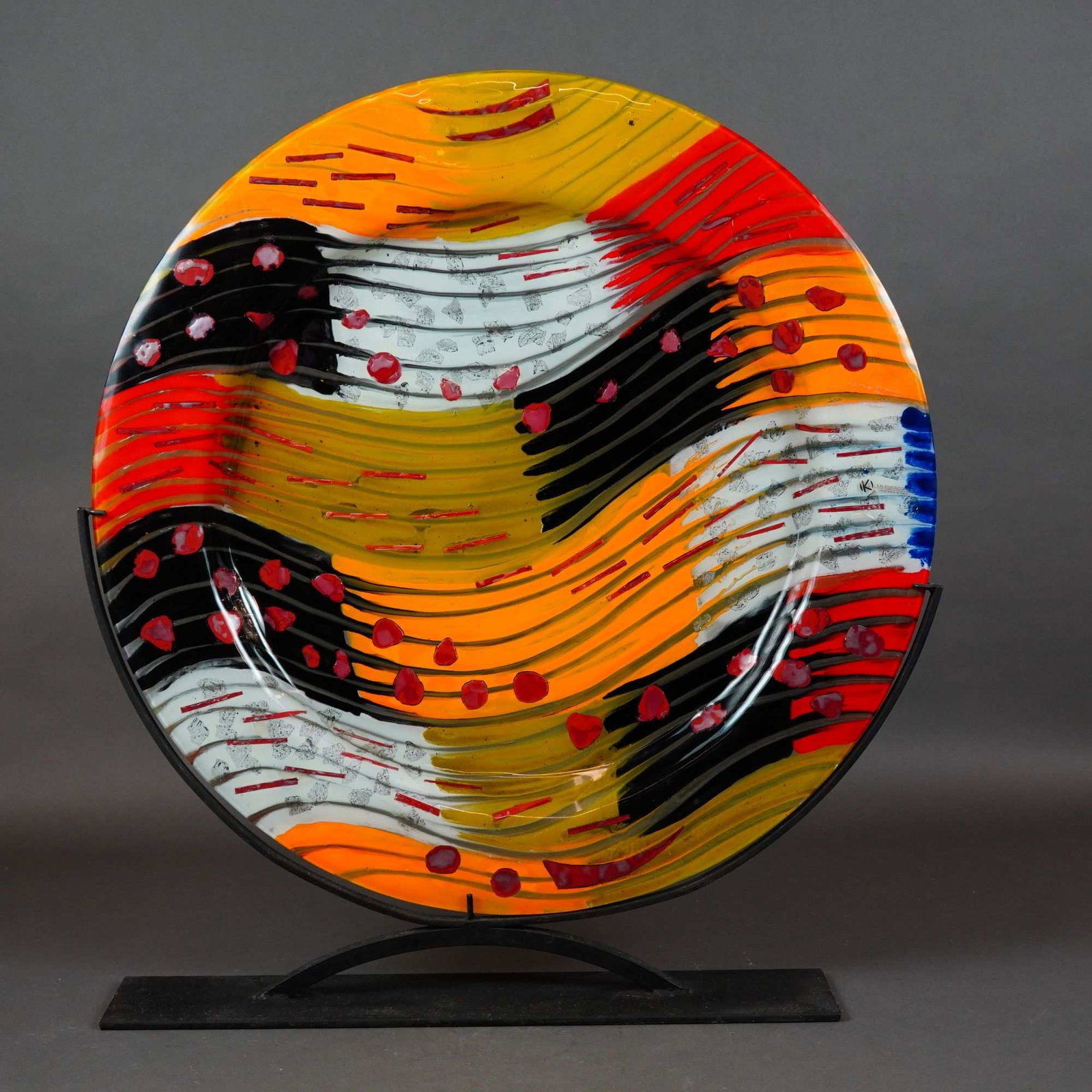 Kaleidoscopio Italian Fused Art Glass Platter with Display Stand: A circular Italian art glass platter or charger produced by the Kaleidoscopio studio. The piece is crafted using fused and slumped glass techniques, featuring an abstract composition of dynamic, sweep