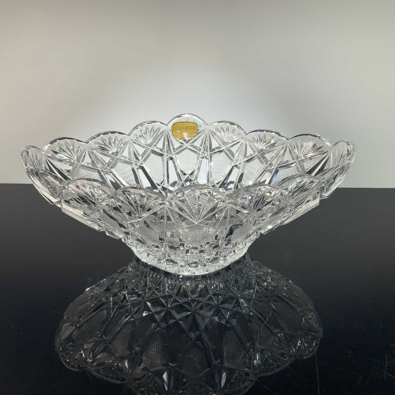 West German Hand Cut 24% Lead Crystal Sawtooth Star Centerpiece Bowl: This large centerpiece bowl is constructed from 24% lead crystal and features a hand-cut geometric design. The form consists of a broad, flaring body with a deeply scalloped sawtooth rim, resting on a