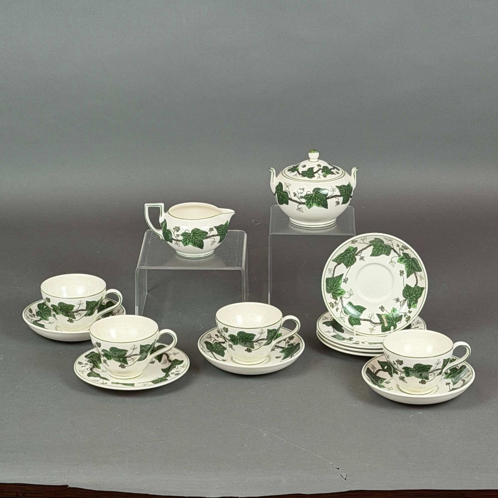 14pc Wedgwood Napoleon Ivy Pattern Tea Service: A 14pc Wedgwood Napoleon Ivy set crafted from cream-colored earthenware, or Queensware, featuring a green transfer-printed border of ivy leaves and berries on brown vine stems. This service is a repro