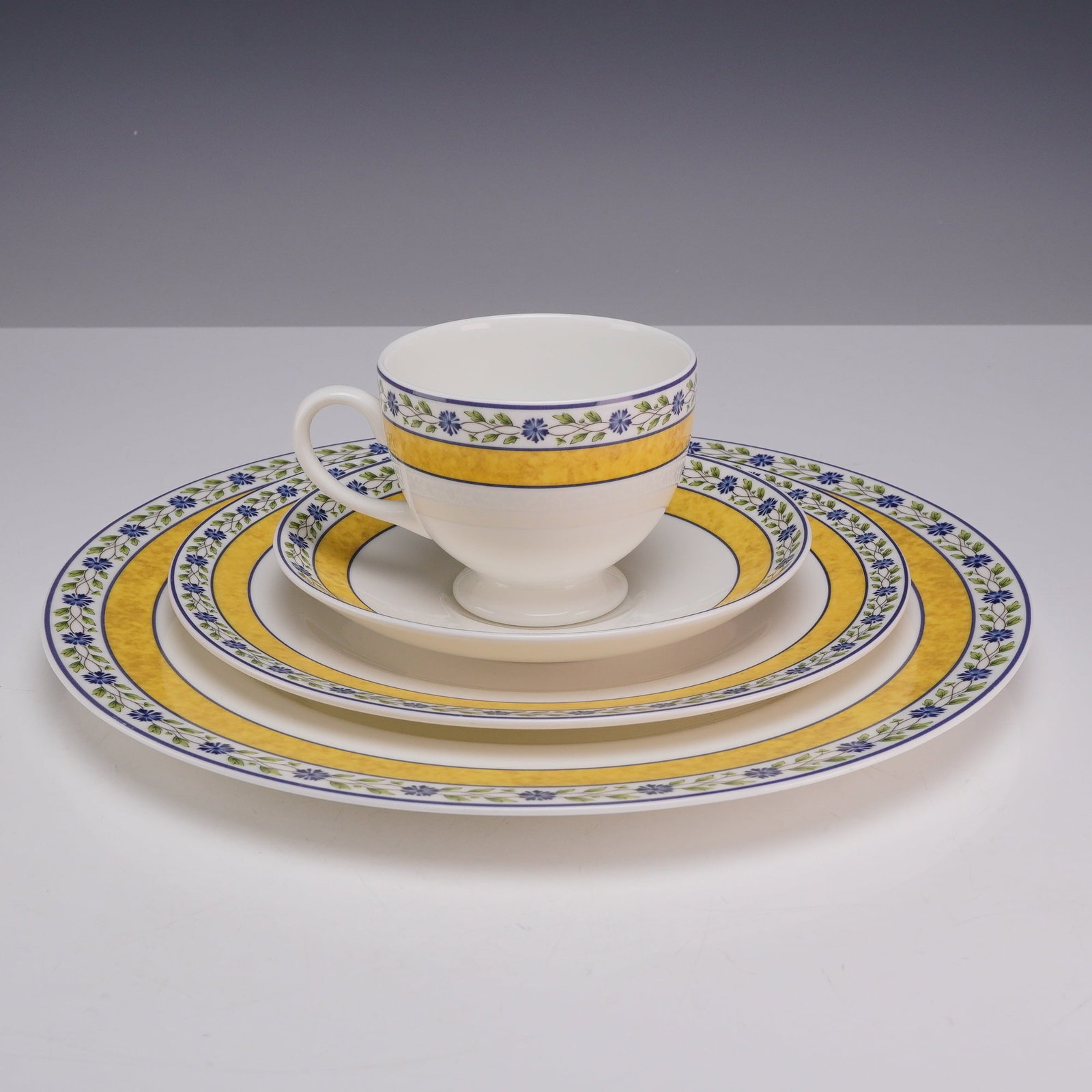 4 Piece Set of Wedgwood Bone China Plates and Teacup, Mistral: Partial place setting of fine bone china manufactured by Wedgwood in the Mistral pattern. The set includes one dinner plate, one salad or luncheon plate, one footed teacup, and one saucer. The