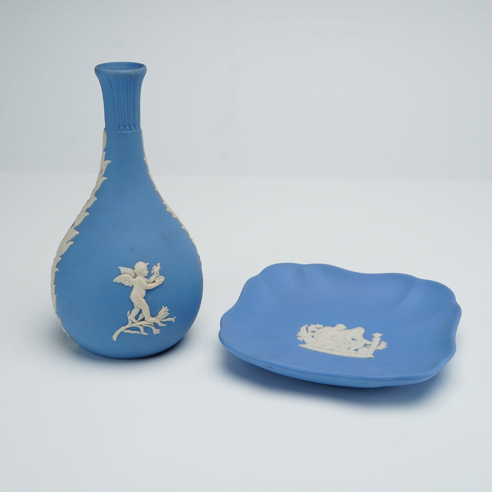2pc Wedgwood Blue Jasperware Bud Vase and Dish: This lot features two Wedgwood items in the classic light blue Jasperware style, consisting of a bud vase and a pin dish. Both pieces are crafted from fine-grained, unglazed stoneware with white