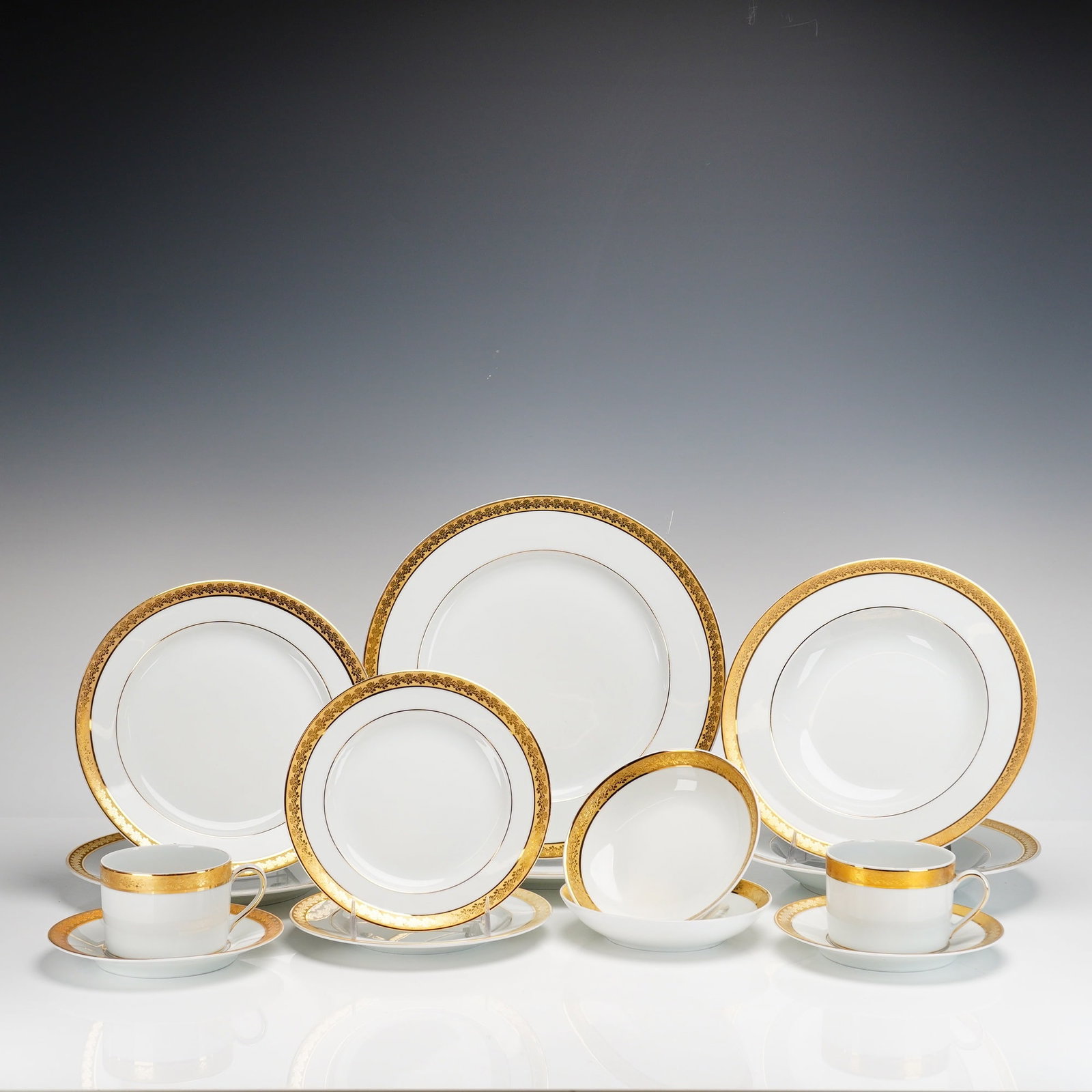 14-Piece Bernardaud Limoges Porcelain Service for 2, Rhapsody Pattern: Crafted from fine white porcelain, the set is characterized by wide, acid-etched gold borders featuring an intricate, repeating floral and foliate scroll motif. Additional fine gold bands accent the i