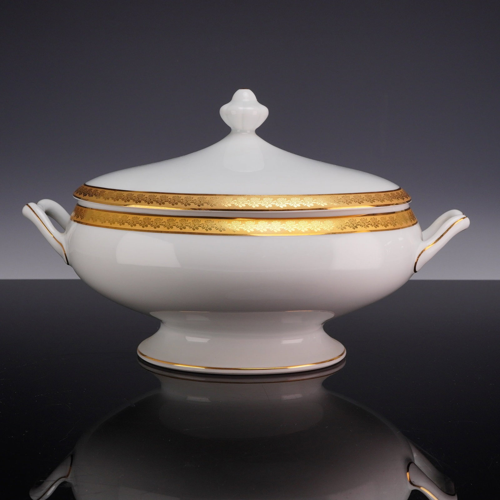 Bernardaud Limoges Porcelain Covered Vegetable in Rhapsody Pattern: A fine porcelain footed and covered oval vegetable dish manufactured by Bernardaud in Limoges, France. The piece features the Rhapsody pattern, which is defined by a wide, gold-encrusted band with a d