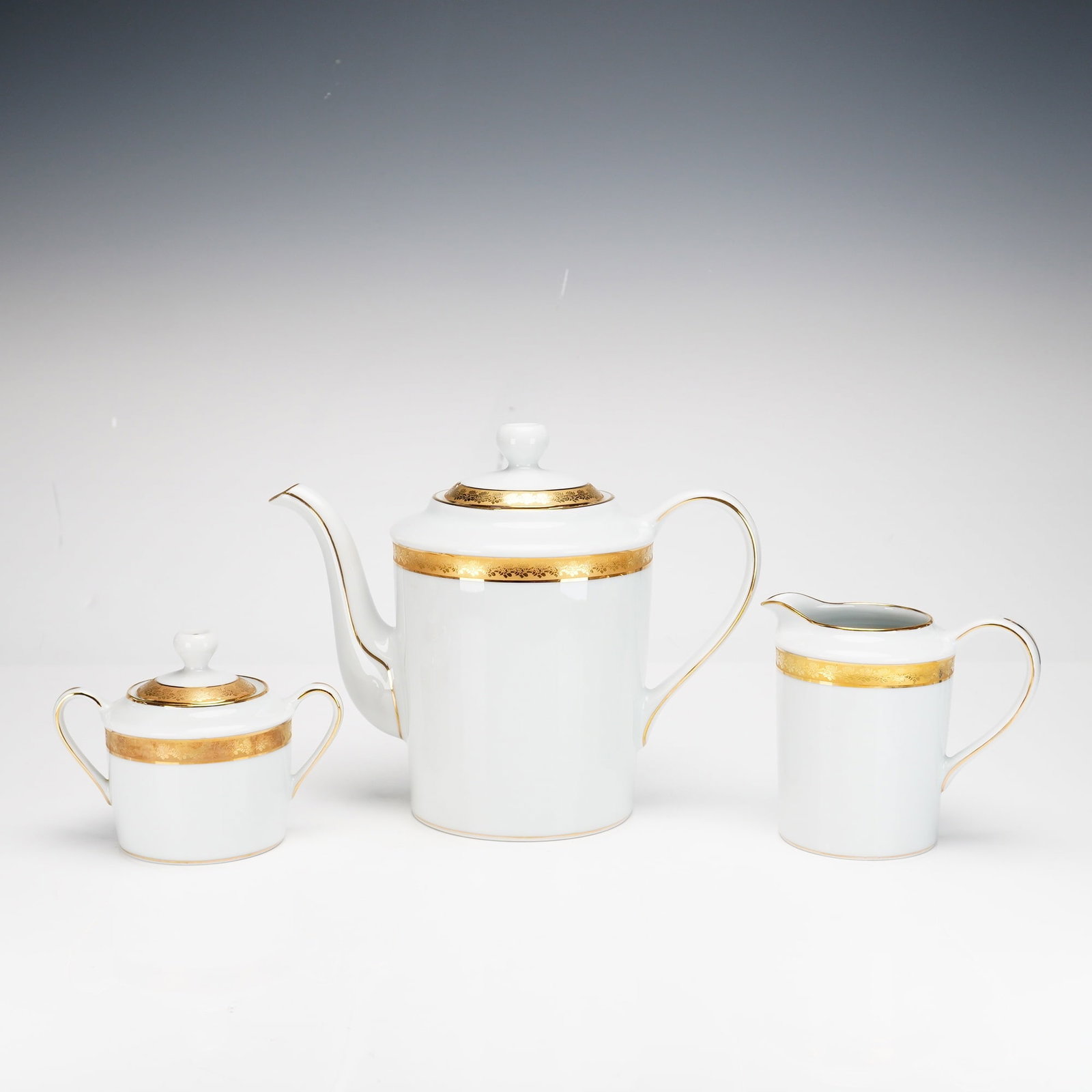 Three Piece Set Bernardaud Limoges Porcelain Coffee Service, Rhapsody Pattern: The set consists of a coffeepot with a fitted lid, a double-handled sugar bowl with a lid, and a cream pitcher. Each piece is crafted from white porcelain in a tapered cylindrical form. The decoration