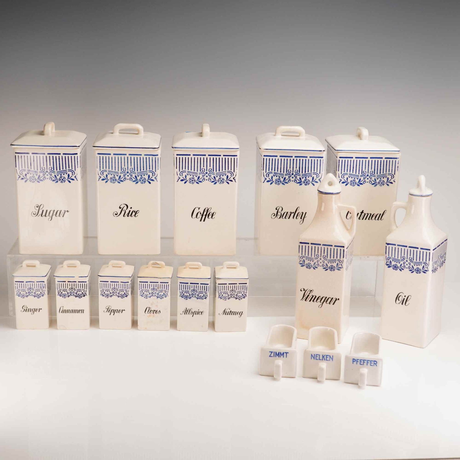 16pc Germany Ceramic Kitchen Storage Set: Ceramic kitchen canister set dating to the early-to-mid 20th century. The set features a white glazed finish with blue floral and geometric decoration and includes large storage canisters, spice jars,