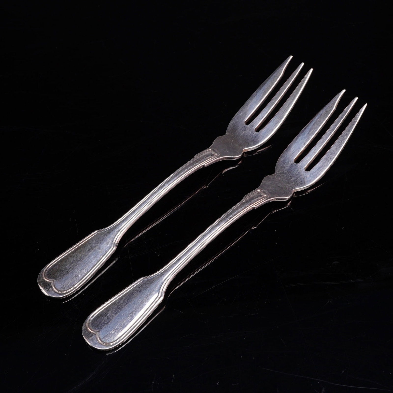 A Pair of Buccellati Italy Silver-Plated Nantucket Pattern Cocktail Forks: A pair of Buccellati silverplated cocktail forks in the Nantucket pattern, manufactured in Italy. These three-tined utensils are designed for cocktail, oyster, or hors d'oeuvres service. Each fork fea