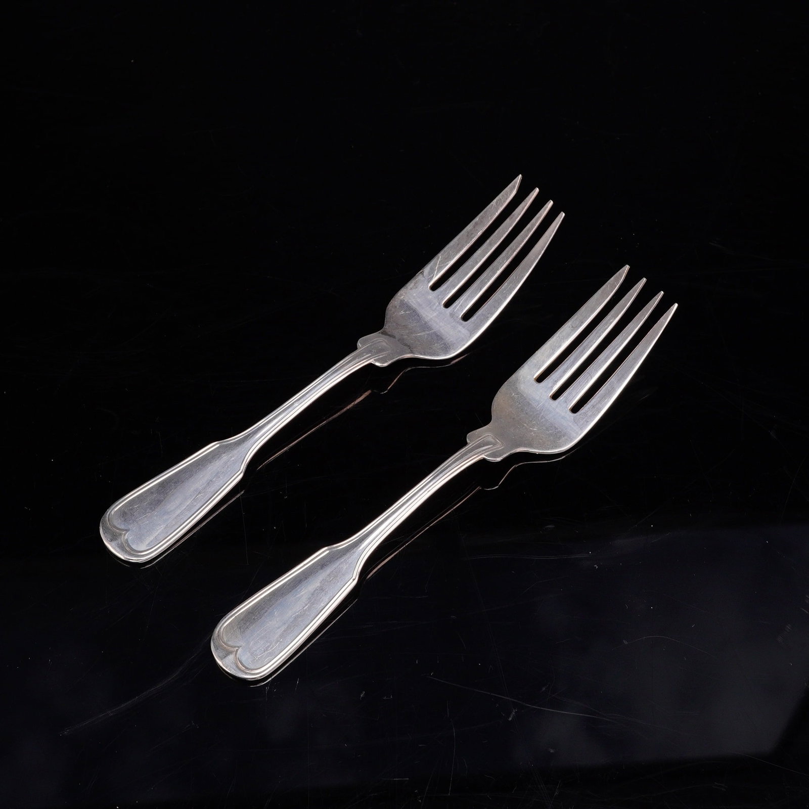 A Pair of Frank W. Smith Silver Co. Sterling Silver Fiddle Thread Pattern Forks: This set features two sterling silver forks designed in the classic Fiddle Thread pattern. The handles are characterized by a fiddle-shaped silhouette, a raised thread border along the edges, and a he