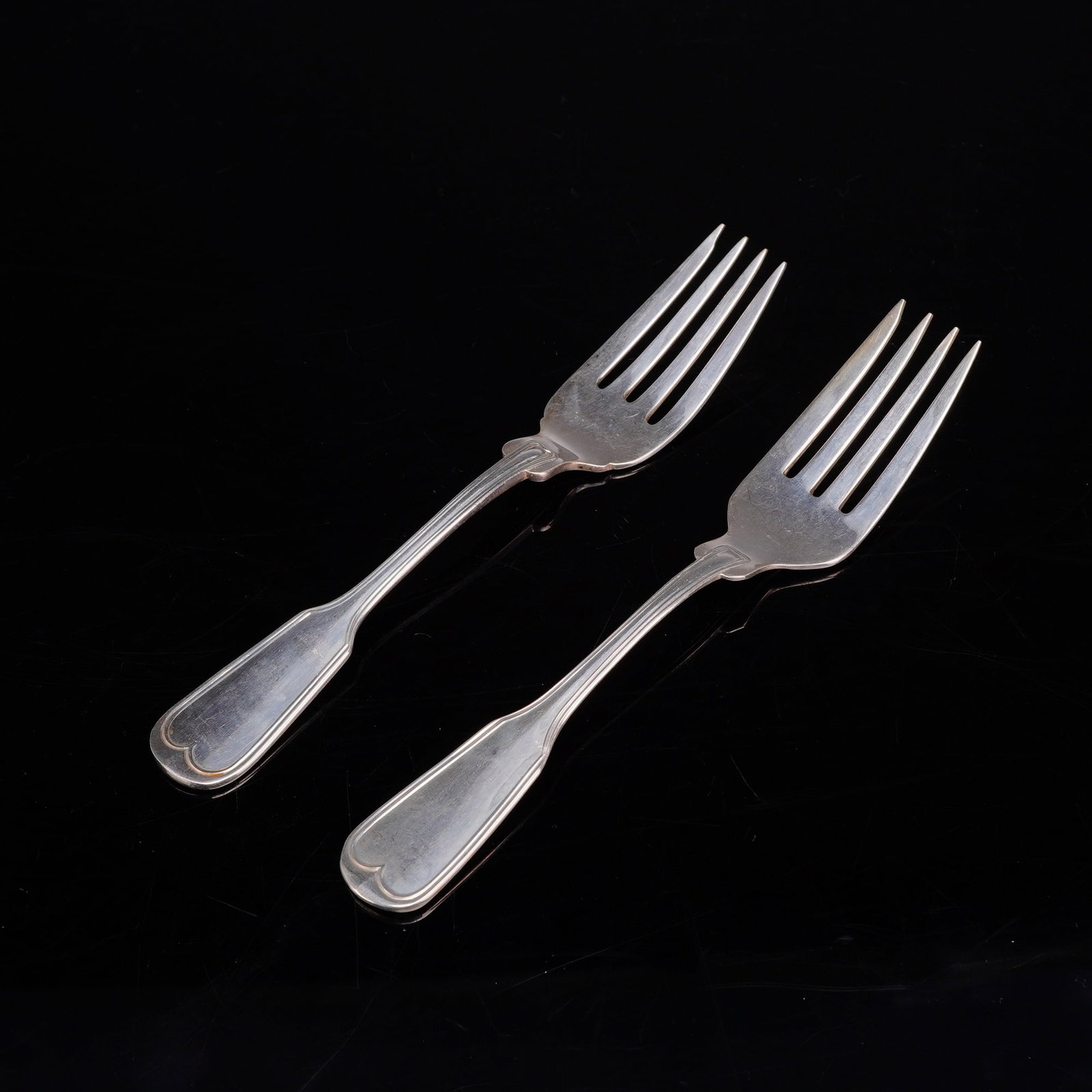 A Pair of Frank W. Smith Silver Co. Sterling Silver Salad Forks: This pair of sterling silver salad forks was produced by Frank W. Smith Silver Co. The forks are designed in the Fiddle Thread pattern. Each fork features a fiddle-shaped handle characterized by a thr