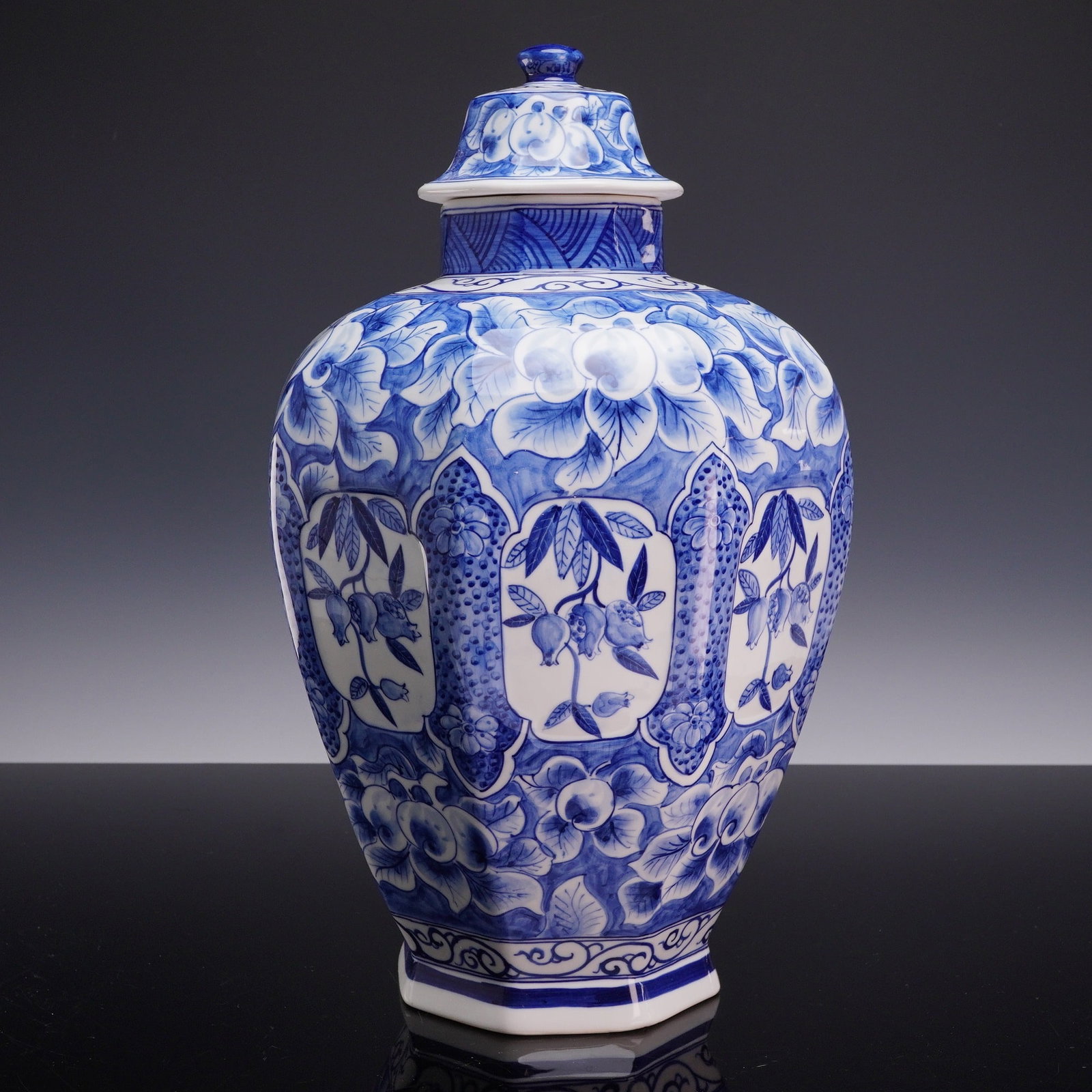 Large Blue and White Octagonal Lidded Temple Jar: This large octagonal lidded temple jar is constructed of porcelain and decorated in underglaze blue. The vessel features an eight-sided baluster form with a high, rounded shoulder tapering to a facete