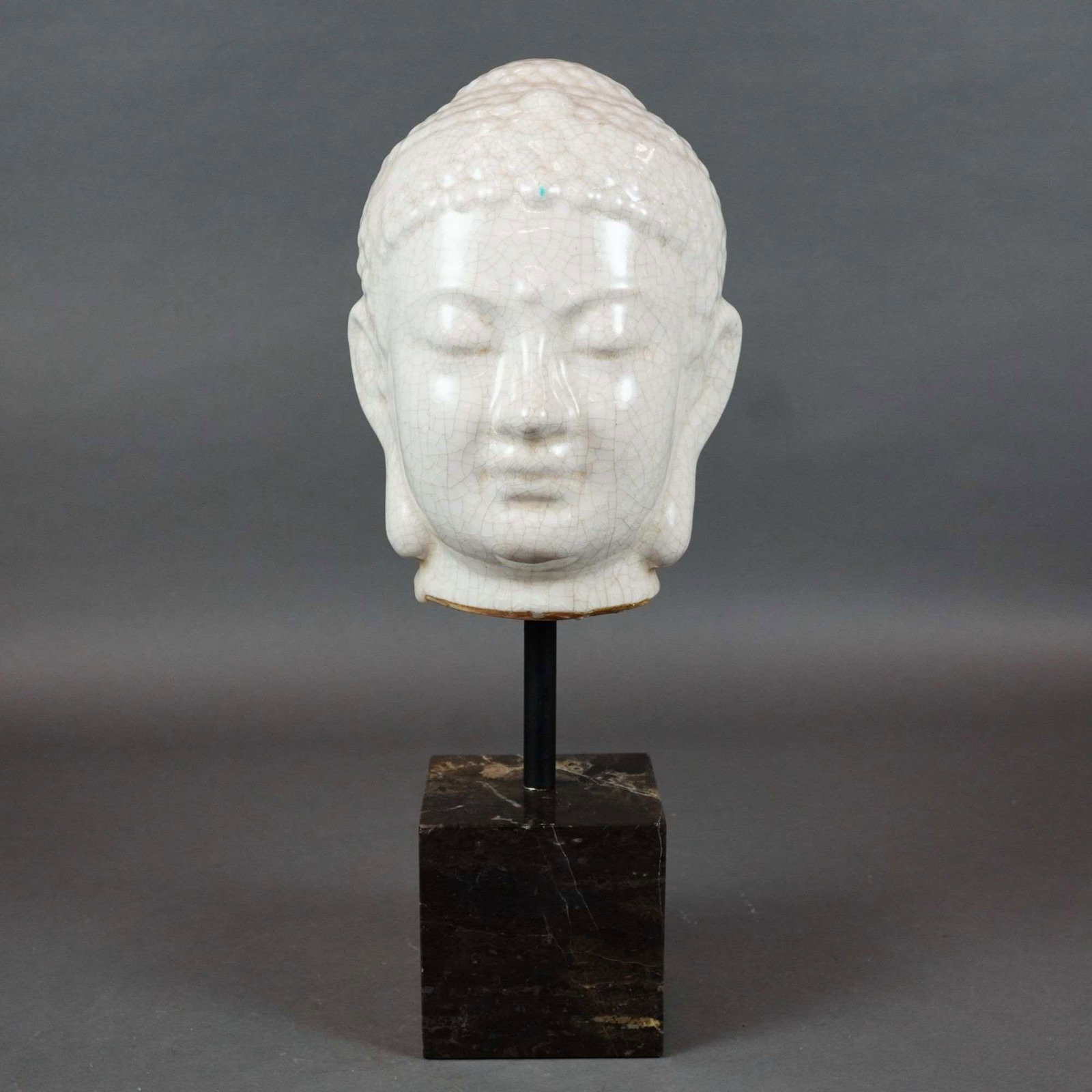 Modern Ceramic Buddha Head with White Crackle Glaze on Marble Stand: A contemporary decorative ceramic bust depicting the head of a Buddha, finished in a creamy-white crackle glaze in the style of traditional Chinese Ge-ware. The serene facial features include downcast