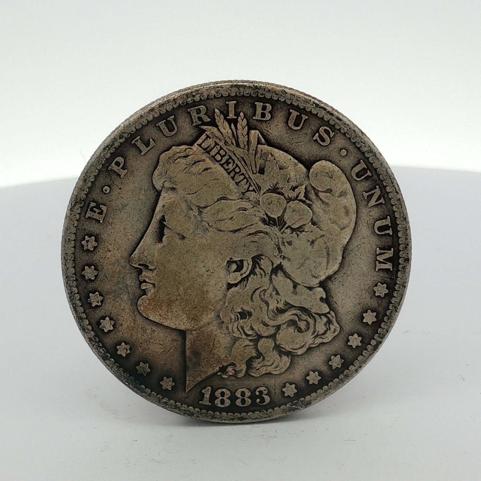 1883 US One Dollar Morgan Silver Dollar, Circulated: This US Morgan silver dollar was struck in 1883 at the Philadelphia Mint, as indicated by no mint mark located on the reverse. The coin is composed of 90 percent silver and 10 percent copper. The obve