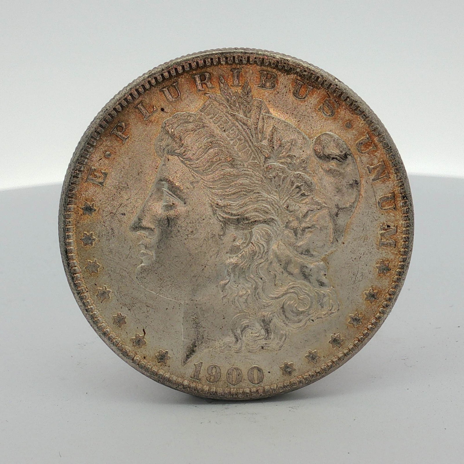 1900-O US Morgan Silver Dollar: This US Morgan dollar was struck at the New Orleans Mint in 1900. The coin is composed of 90% silver with a reeded edge. The obverse features the Liberty head design and the reverse displays the eagle