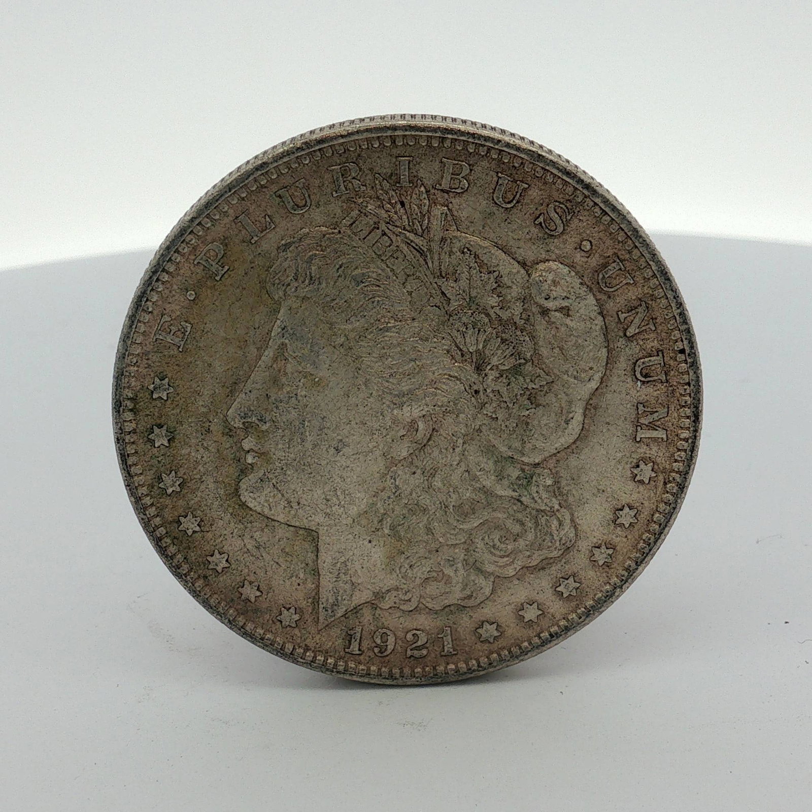1921 US One Dollar Morgan Silver Dollar, Circulated: This 1921 US Morgan dollar is struck in a 90% silver composition (0.900 fineness). The coin features the Morgan dollar obverse and reverse designs. Inscriptions include E PLURIBUS UNUM and the date 19
