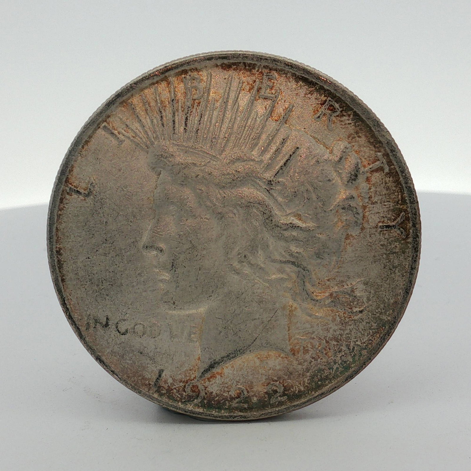 1922-D US One Dollar Silver Peace Dollar, Circulated: 1922-D US silver Peace dollar struck at the Denver Mint. The coin is struck in 0.900 fine silver and features a reeded edge. The obverse features the Liberty head design with inscriptions LIBERTY, IN 