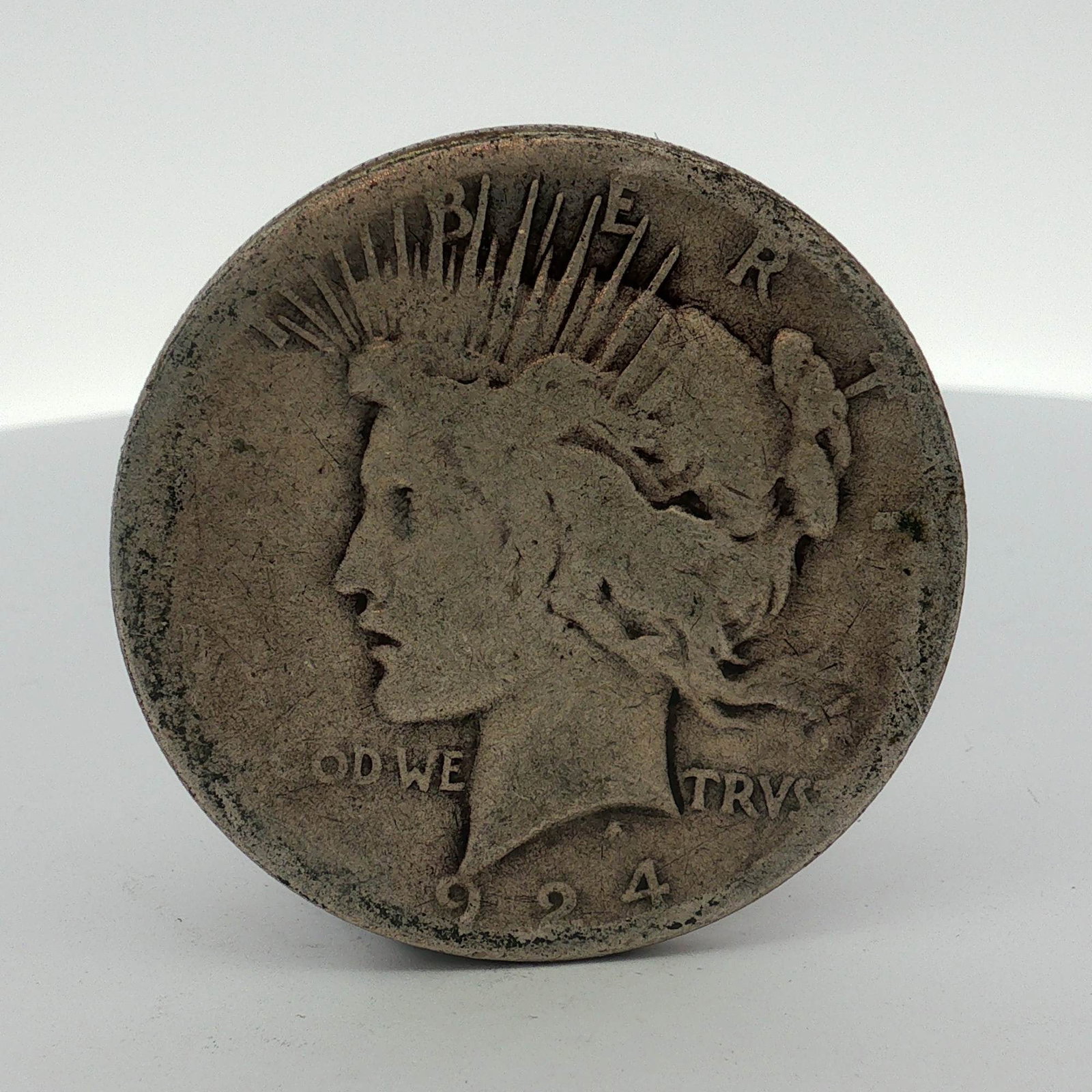 1924-S US One Dollar Peace Silver Dollar Coin, Circulated: This US 1924 Peace silver dollar is a raw specimen struck in .900 silver at the Philadelphia mint. The obverse displays the date 1924 and partial inscriptions including IN GOD WE TRUST. The reverse fe