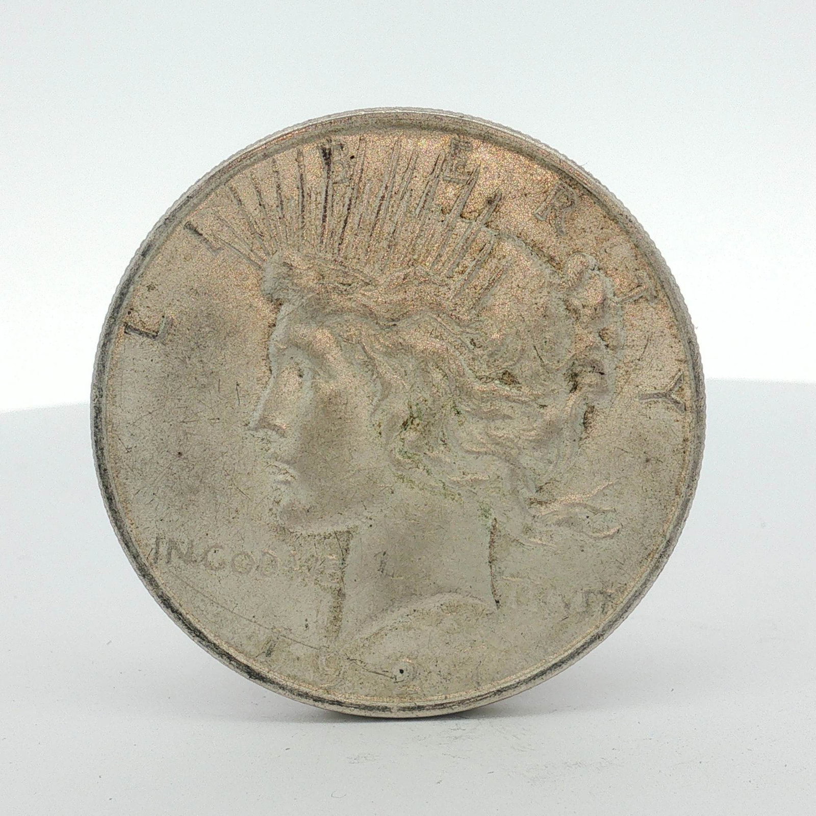 1927-D US One Dollar Silver Peace Dollar, Circulated: This US Peace silver dollar is dated 1927 and was struck at the Denver mint. The coin is composed of 90% silver and 10% copper (0.900 fine silver). It features the Peace dollar obverse and reverse des