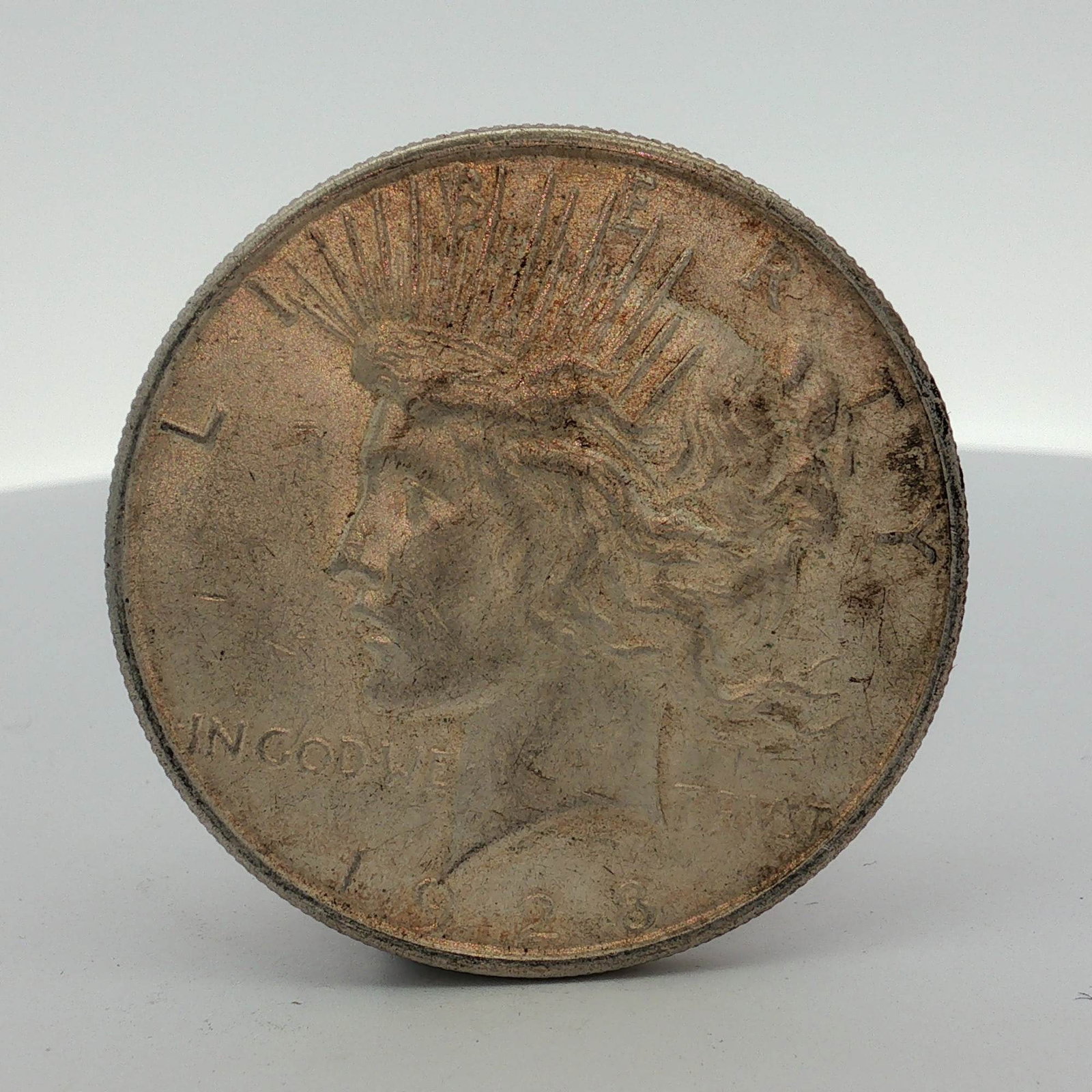 1928-S US Peace Silver Dollar: This US 1928-S Peace silver dollar was struck at the San Francisco Mint. The coin features the standard Peace dollar design. The obverse displays a left-facing profile of Liberty wearing a radiate cro