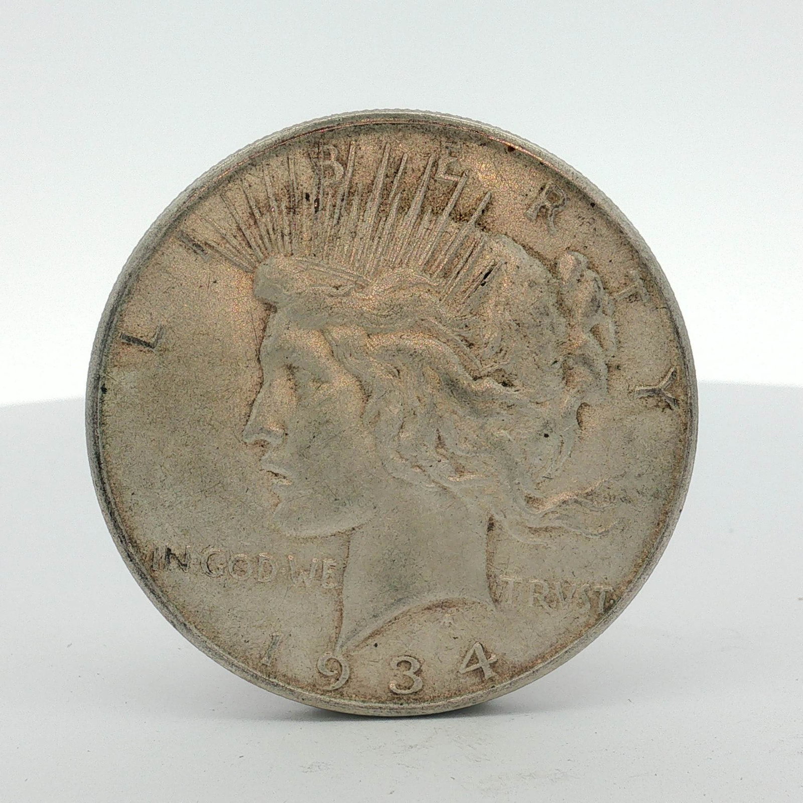 1934-D US One Dollar Silver Peace Dollar, Circulated: This US Peace dollar was produced at the Denver Mint in 1934. The coin is struck in .900 fine silver. The obverse features the Peace dollar design type with the date 1934 and the inscription IN GOD WE