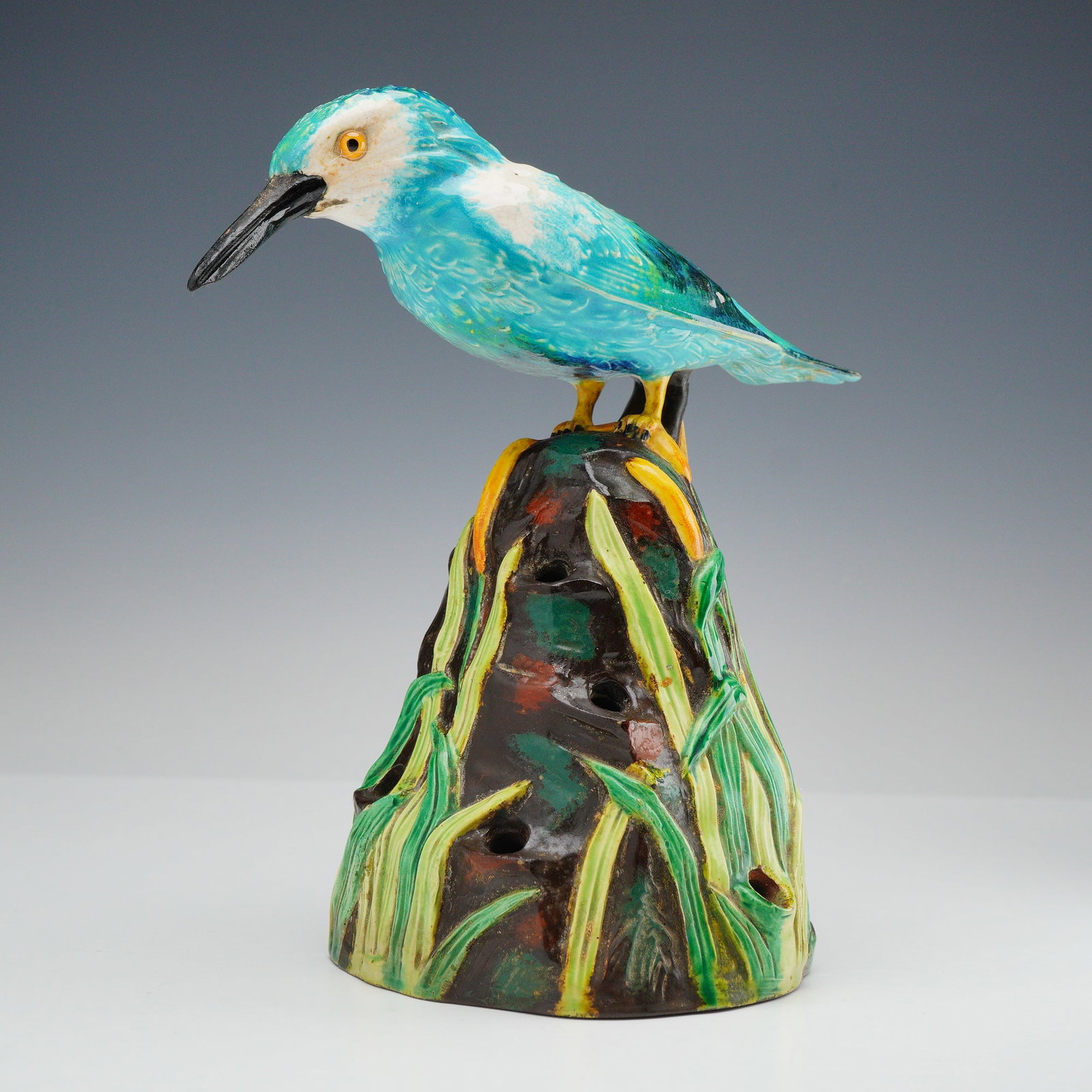 Wedgwood Majolica Kingfisher Flower Frog: A Wedgwood majolica glazed earthenware flower frog depicting a kingfisher. The bird is modeled with turquoise and mottled blue plumage, a white throat, a long black beak, and yellow-rimmed eyes. It is