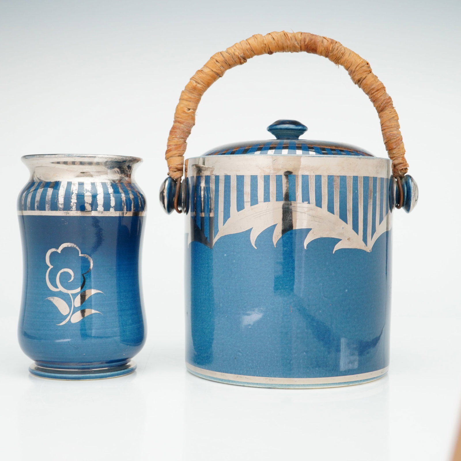 Two Wedgwood Blue Veronese Silver Overlay Biscuit Barrel and Vase: This two-piece set is identified as Wedgwood and consists of a covered jar and a vase. The items are constructed of ceramic with a mottled blue glaze and decorated with silver overlay applied in an Ar
