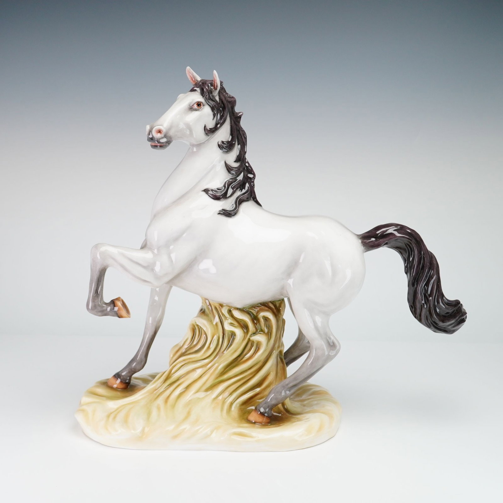 Wedgwood The Barlaston Collection Bone China Horse Figurine: This glazed bone china figurine depicts a rearing horse supported by a central mound of stylized long grass. The horse features a white body with gray-shaded lower legs and a dark brown to black mane 