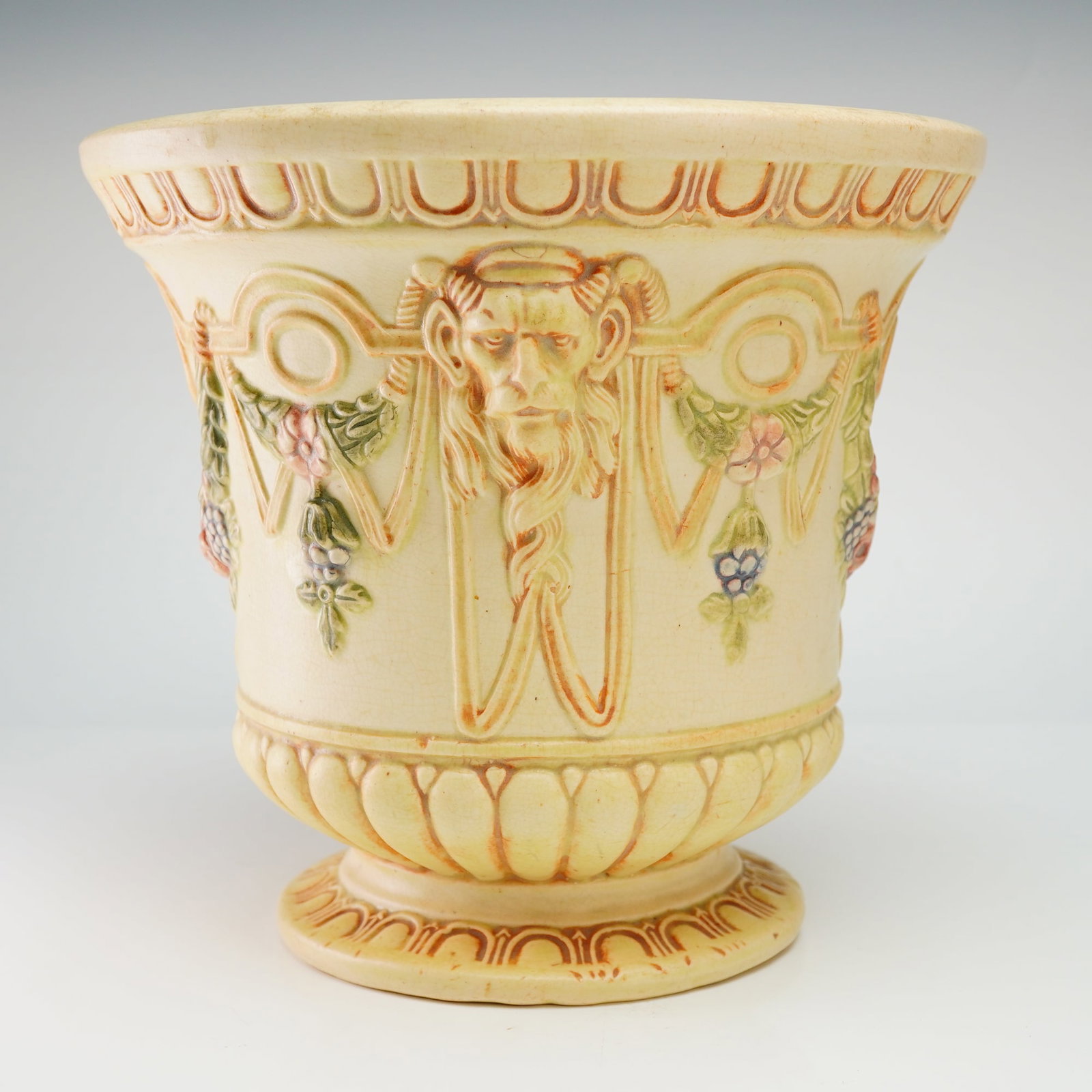 Weller Pottery Flemish Footed Jardiniere: An American Art Nouveau period ceramic footed urn or jardiniere produced by Weller Pottery of Zanesville, Ohio, in the Panella pattern. The vessel is finished in a matte cream glaze with polychrome