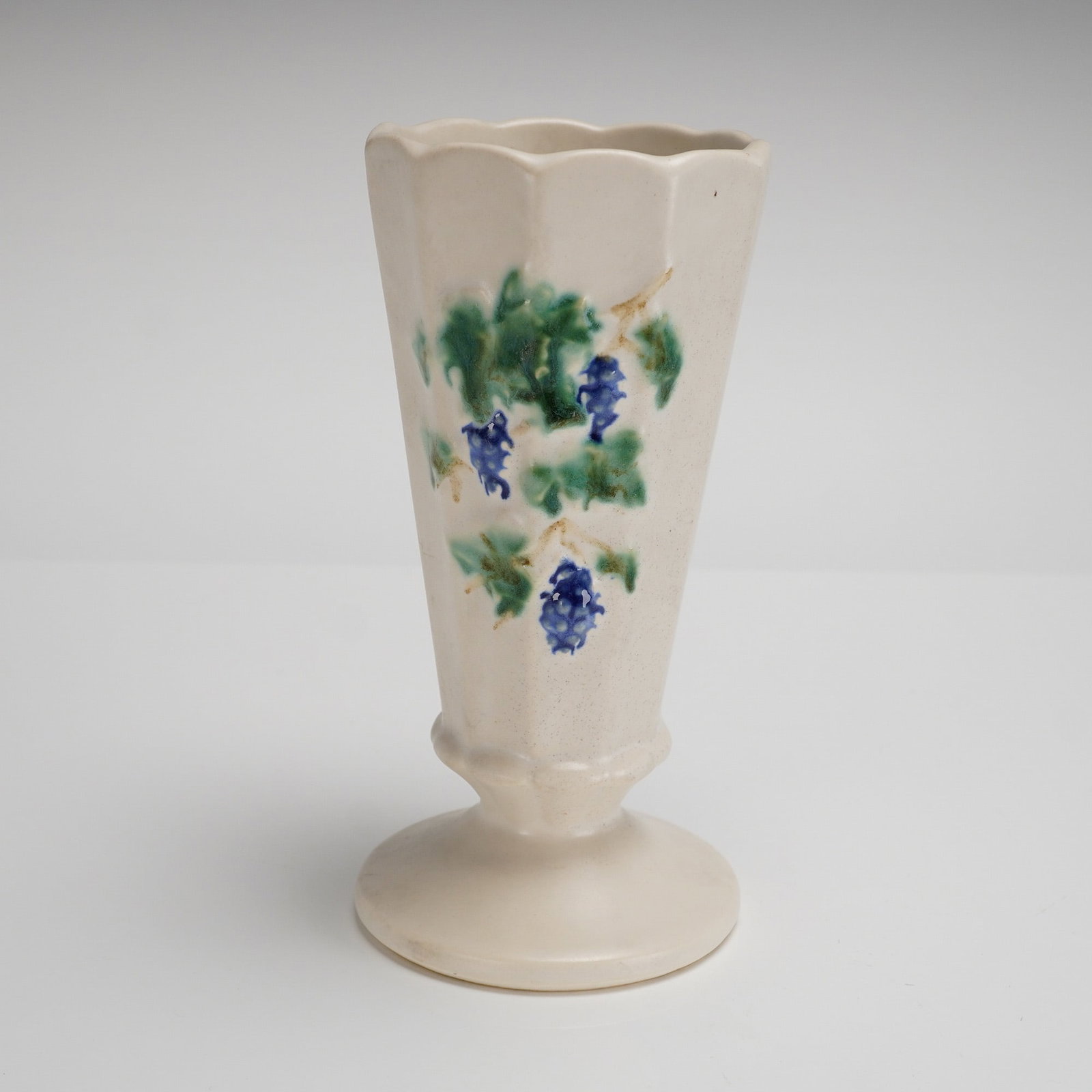 Vintage McCoy Pottery Grapes Paneled Pedestal Vase: A vintage McCoy Pottery Grapes Paneled Vase, attributed circa 1962 based on market consensus and user-provided keywords. The ceramic pedestal vase features a fluted or paneled conical body set upon a 