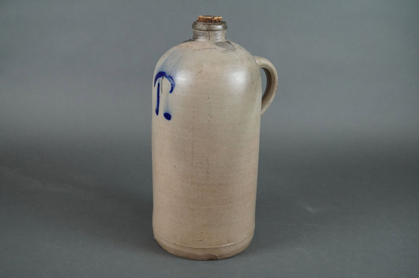 American Salt-Glazed Stoneware Jug w/ Cobalt T Decoration: American utilitarian stoneware jug, salt-glazed, featuring a tall, cylindrical form. The jug is decorated with a large, hand-painted cobalt blue slip-trailed capital letter T applied high on the front