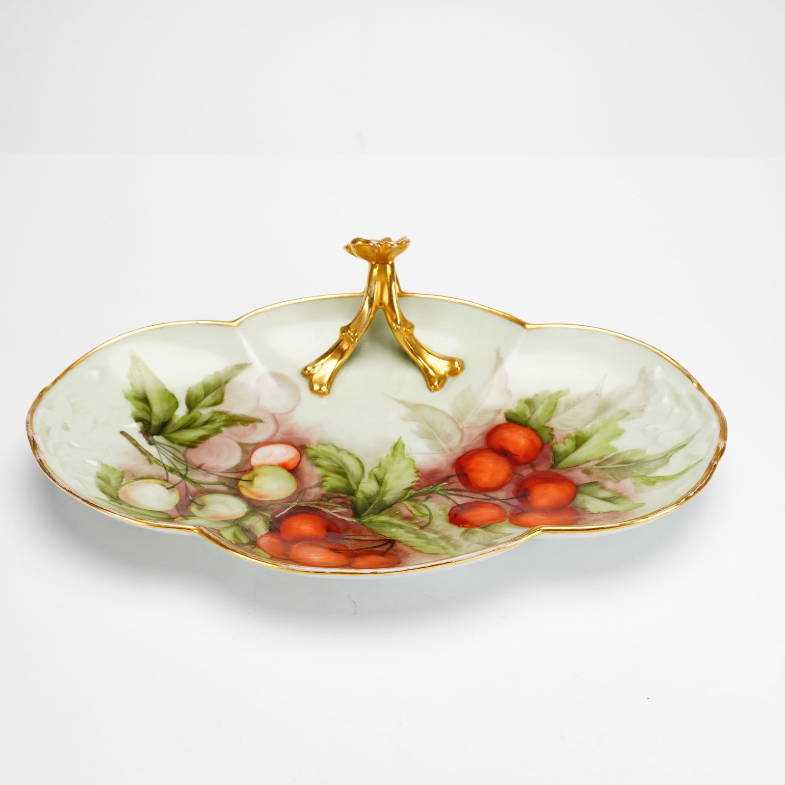 Signed Limoges Porcelain Hand Painted Handled Dish: This hand-painted porcelain dish was manufactured by Jean Pouyat in Limoges, France, and subsequently decorated by artist Mrs. Geo Beck. The dish features a lobed oval form with an undulating rim and 