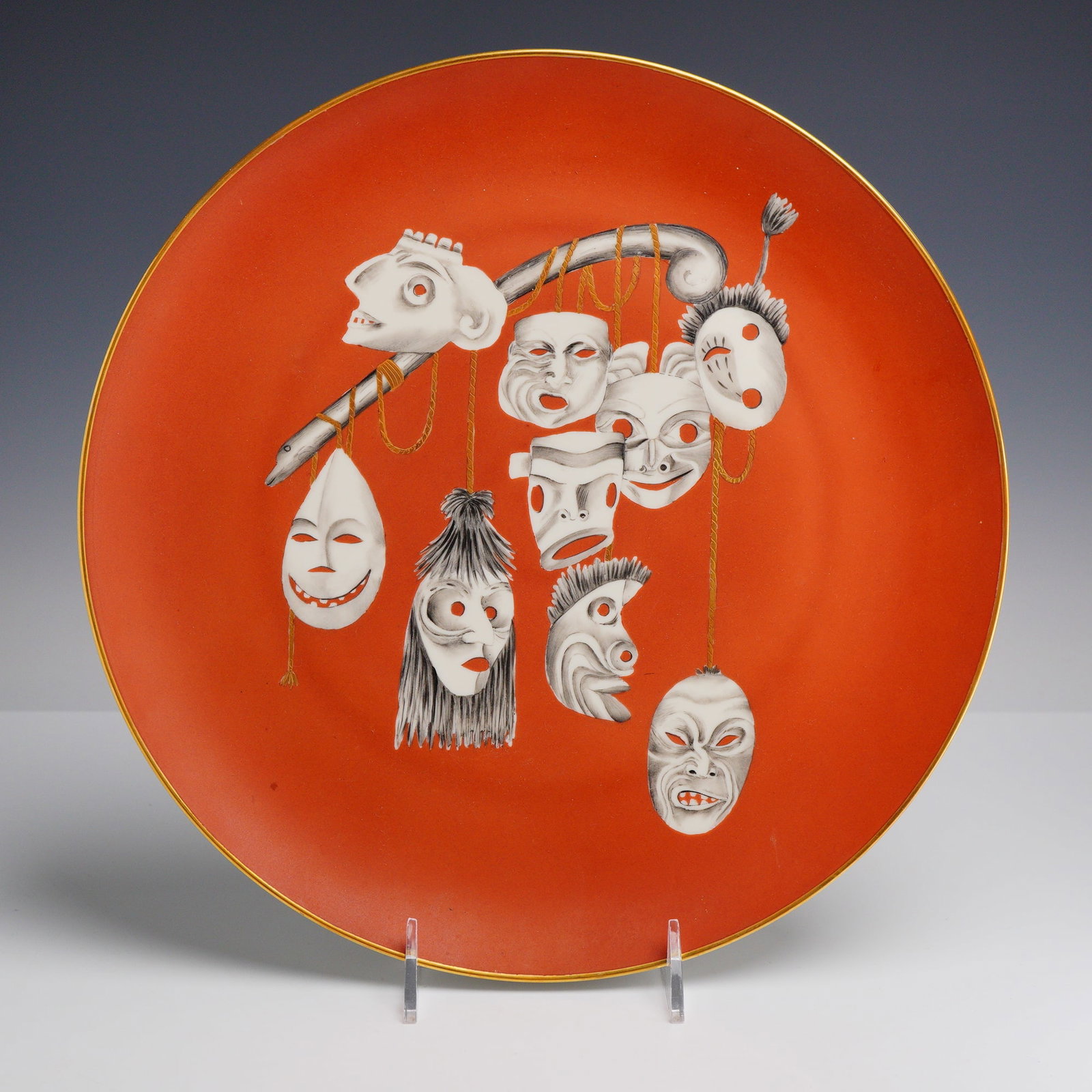 Italian Mid-Century Modern Ceramic Charger by Arrigo Finzi with Mask Decoration: A large circular ceramic charger produced by the Italian firm Finzi, Milan. The piece features a vibrant, matte coral-red ground with a central hand-painted motif. The decoration depicts nine stylized