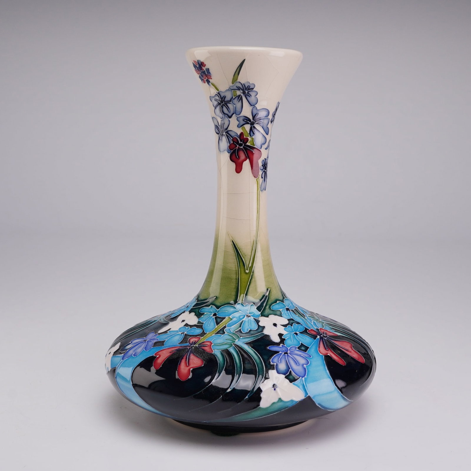 Moorcroft Pottery Floral Bottle Vase dated 2004: A contemporary earthenware bottle vase manufactured by Moorcroft in Stoke-on-Trent, England. The vessel features a tall, slender neck with a flared rim set upon a wide, compressed globular base. The e