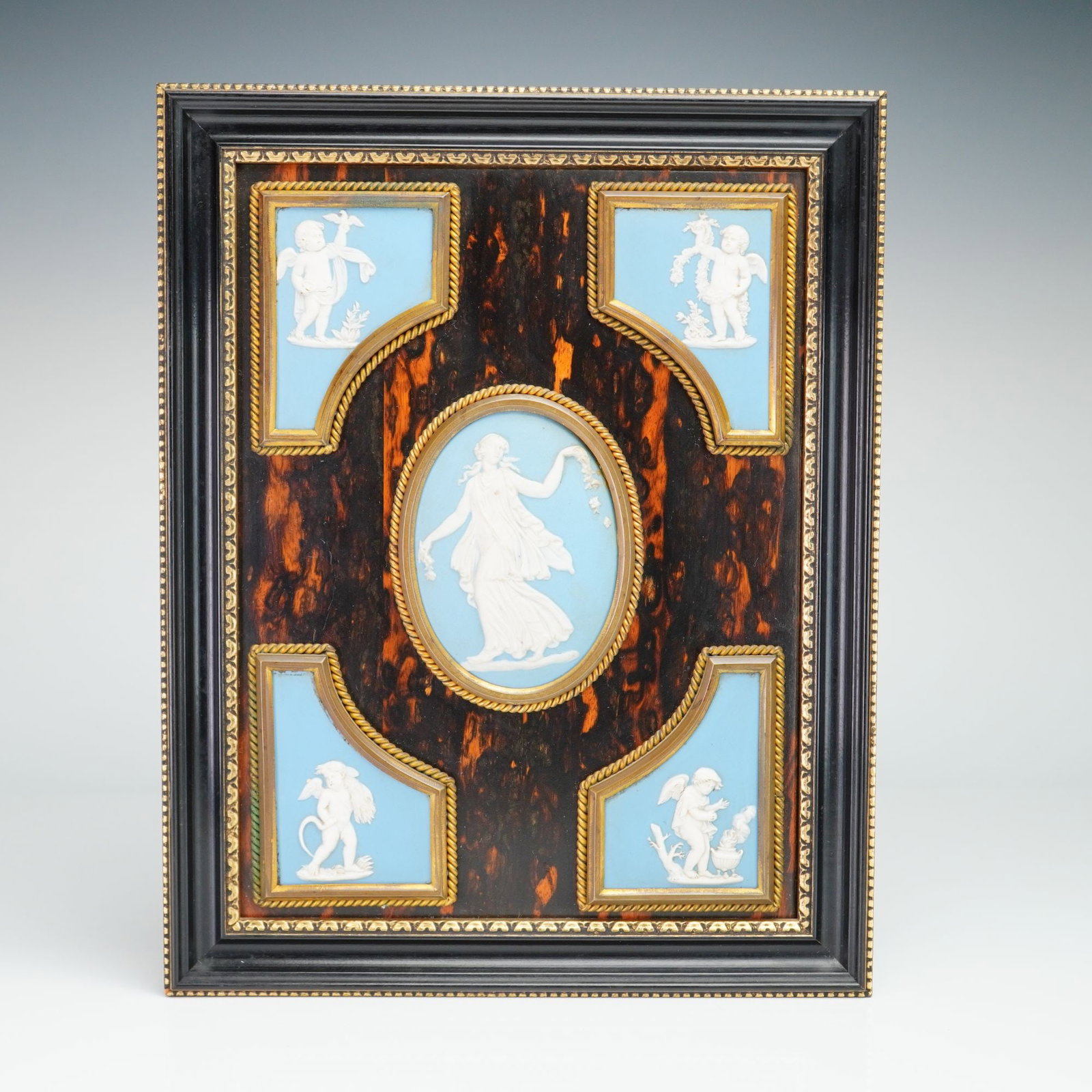 Framed Wedgwood Light Blue Jasperware Plaque: A framed assembly featuring five Wedgwood light blue jasperware plaques with white relief decoration. The central oval plaque depicts a neoclassical dancing female figure, while the four corner plaque