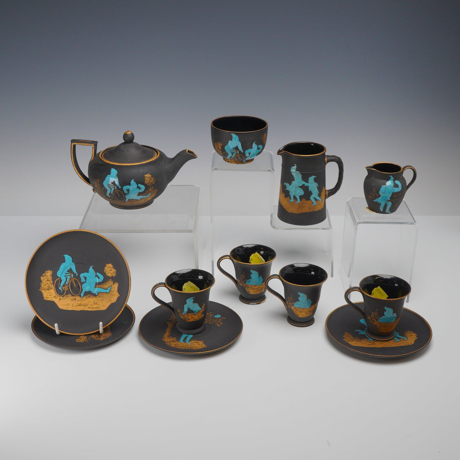 Twelve-Piece Wedgwood Black Basalt Tea Service, Brownies: Wedgwood black basalt tea service featuring whimsical enameled and gilded decoration. This set, originating from the Dr. Ellis F. Rubin and Suzanne Borow Rubin Collection, is crafted from fine-grained