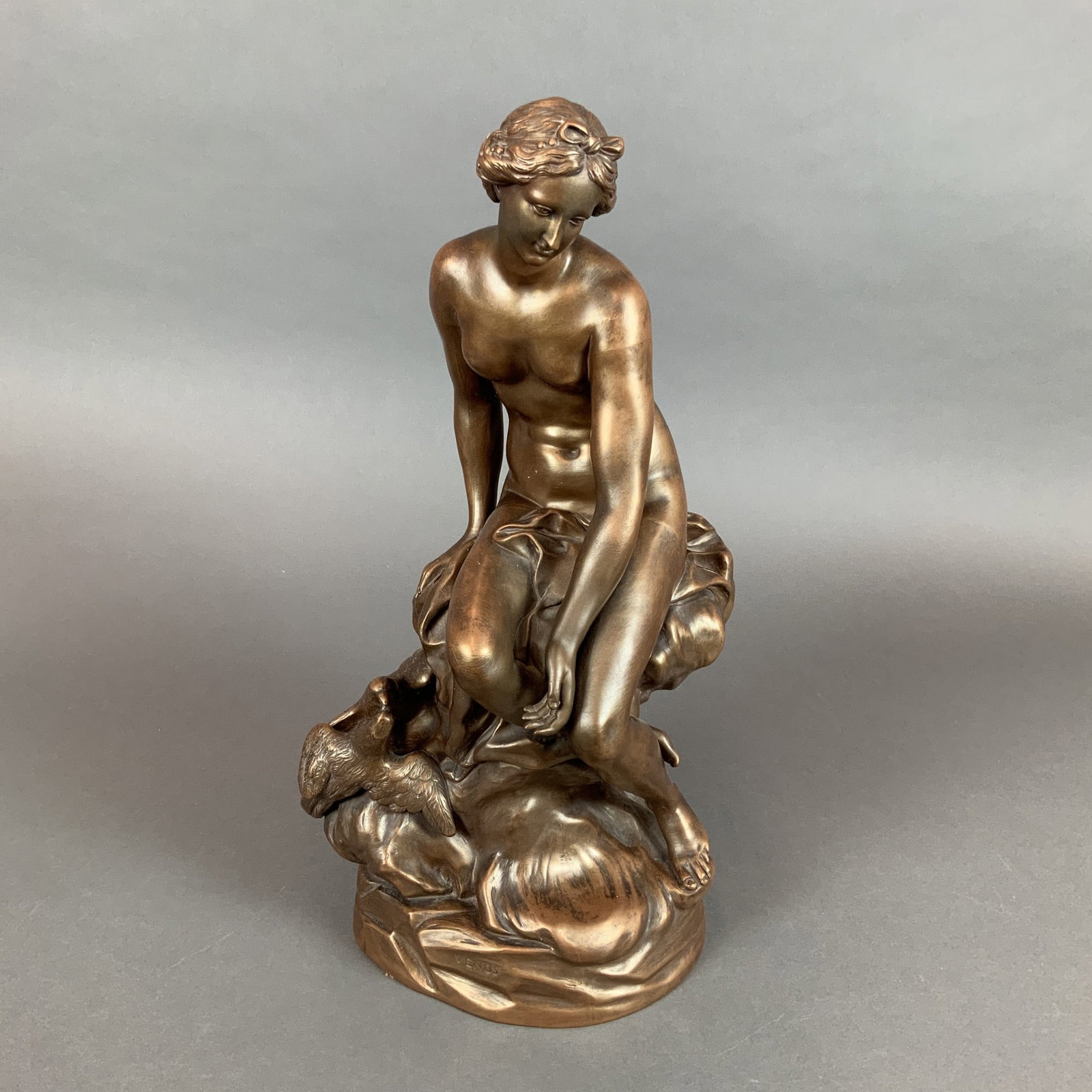 Wedgwood Bronzed Black Basalt Sculpture of Venus: This neoclassical ceramic sculpture is crafted in bronzed black basalt by Wedgwood. The work depicts a crouching figure of Venus accompanied by a two birds. The figure is mounted on an integral circul