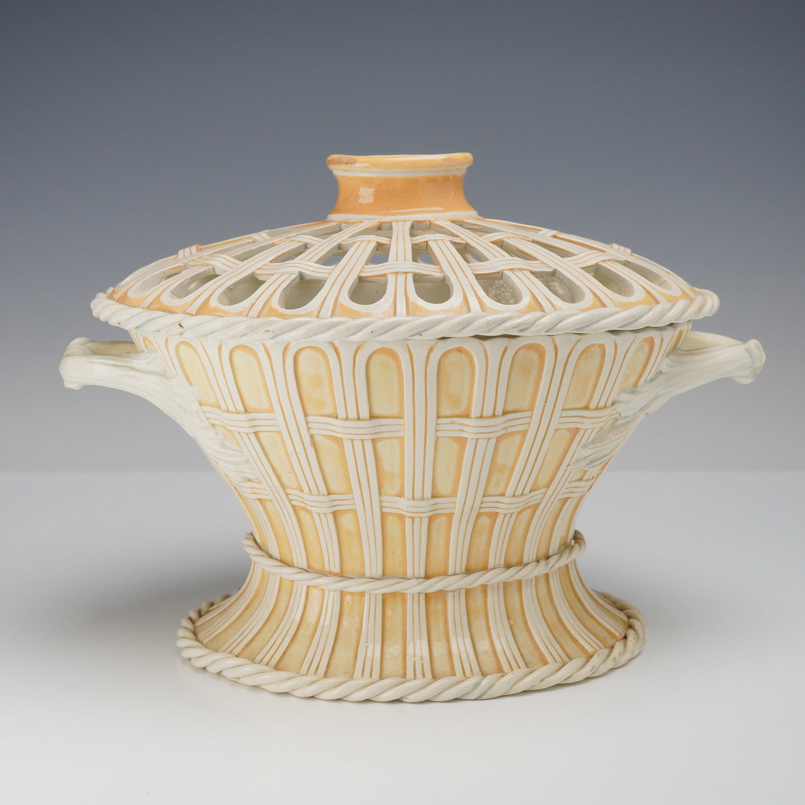 Wedgwood Majolica Creamware Pierced Chestnut Basket and Cover: A Wedgwood creamware lidded chestnut basket featuring a classic oval form with a high-domed pierced lid. The vessel is constructed with a flared footed base and a tapering body adorned with an overall